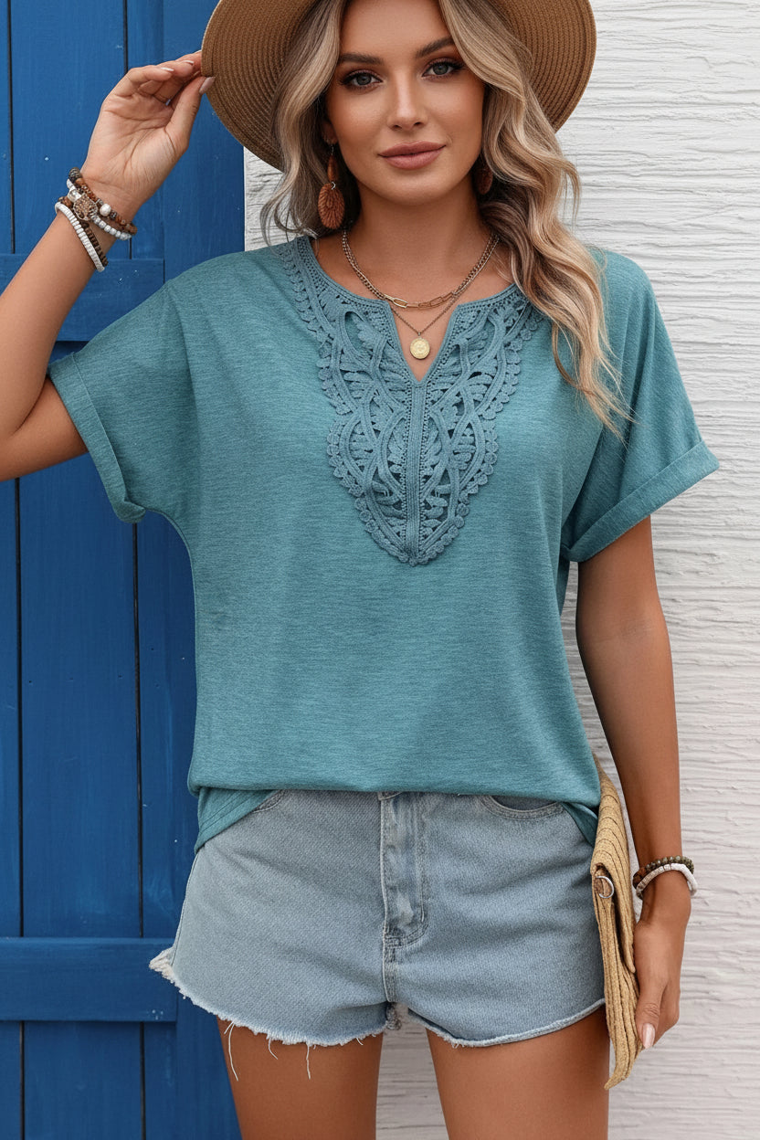 Woman wearing a teal lace-trimmed top and denim shorts against a blue door.