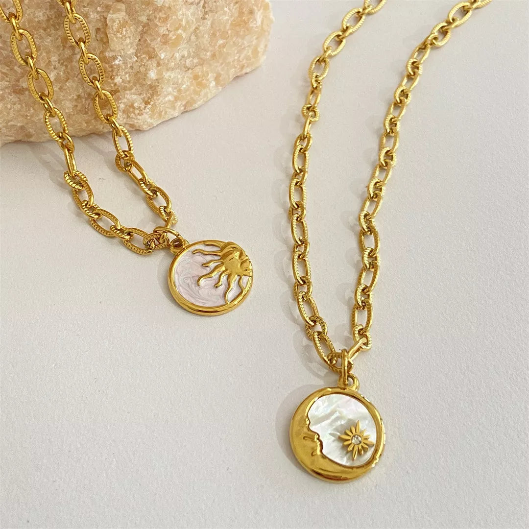 Two gold necklaces with circular pendants on a light background