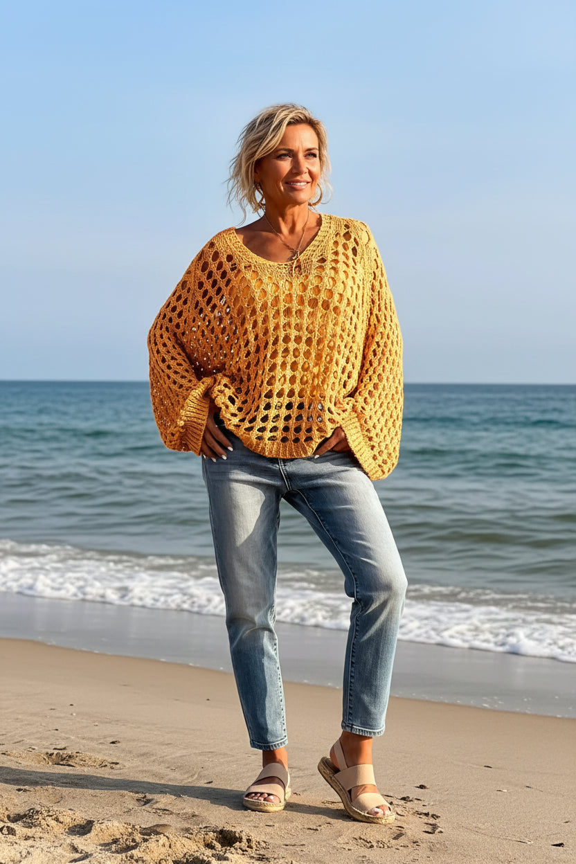 Person wearing a yellow crochet sweater by the ocean