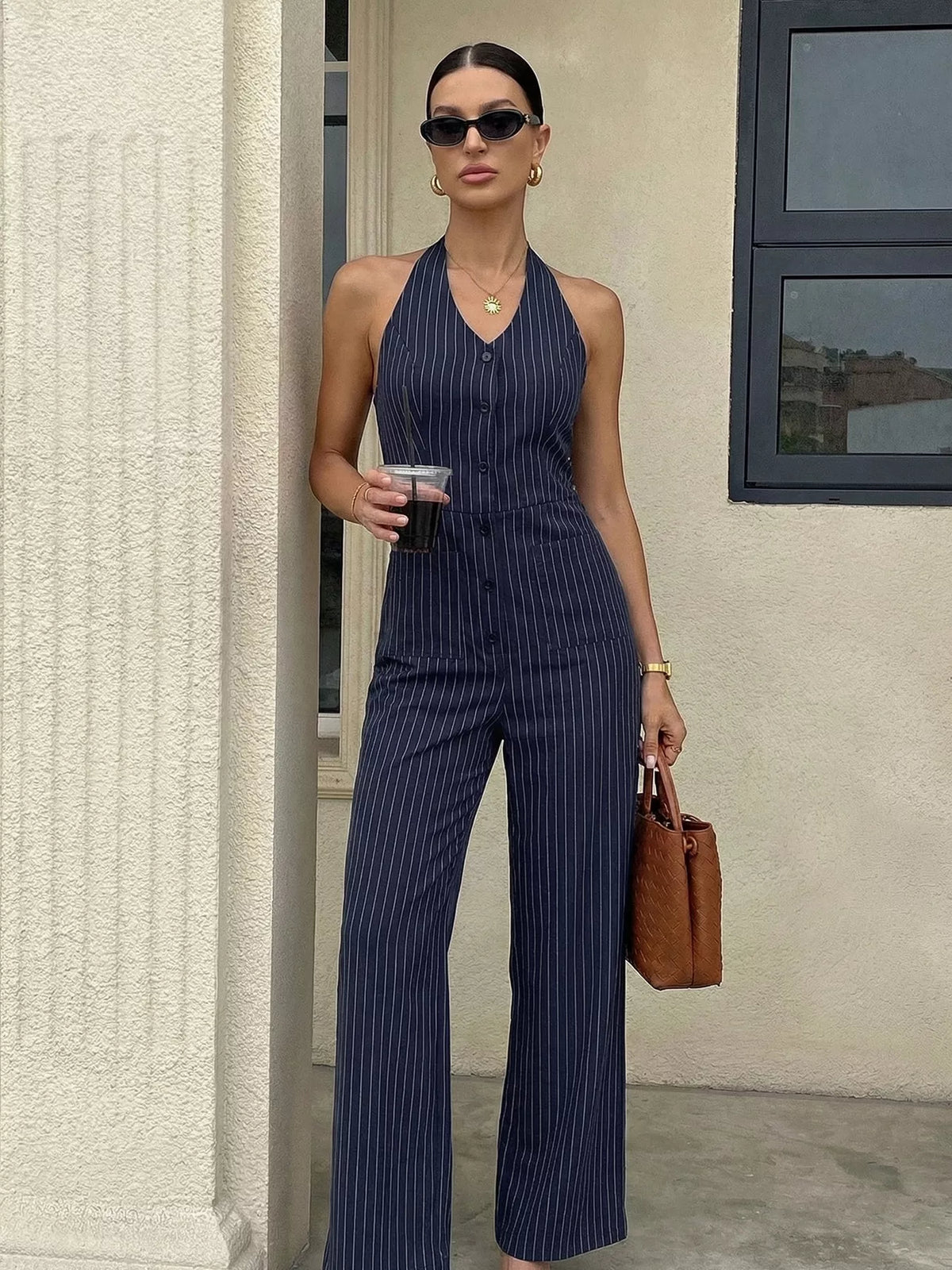 Woman in a navy pinstripe jumpsuit standing outdoors.