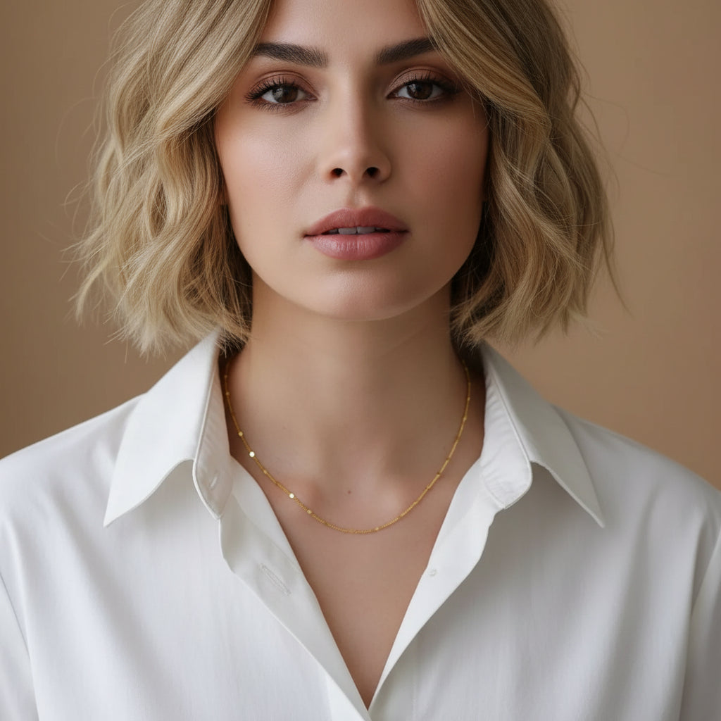 Gold necklace on a person wearing a white shirt