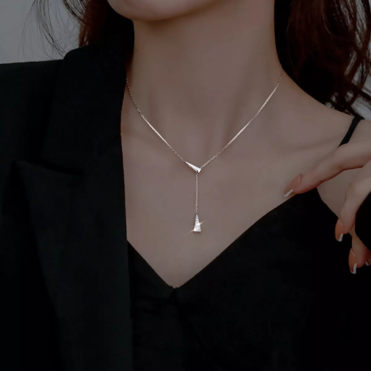 Silver necklace with a pendant worn by a person against a dark background