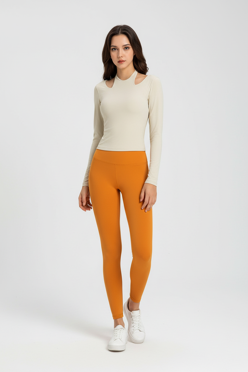 Cream ribbed cutout shoulder top paired with burnt orange high waist leggings and white sneakers