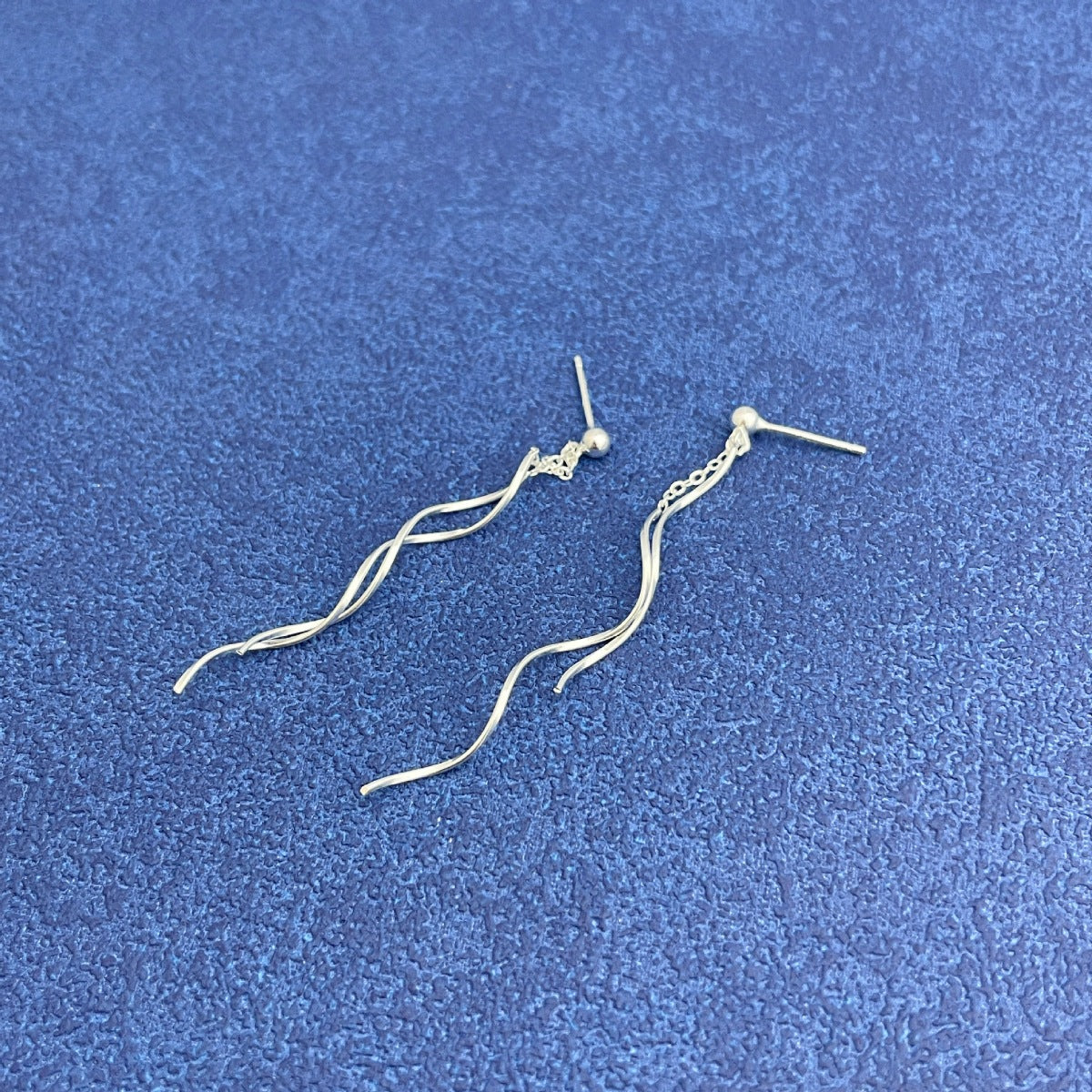 Close-up of fluid wave design on sterling silver statement earrings