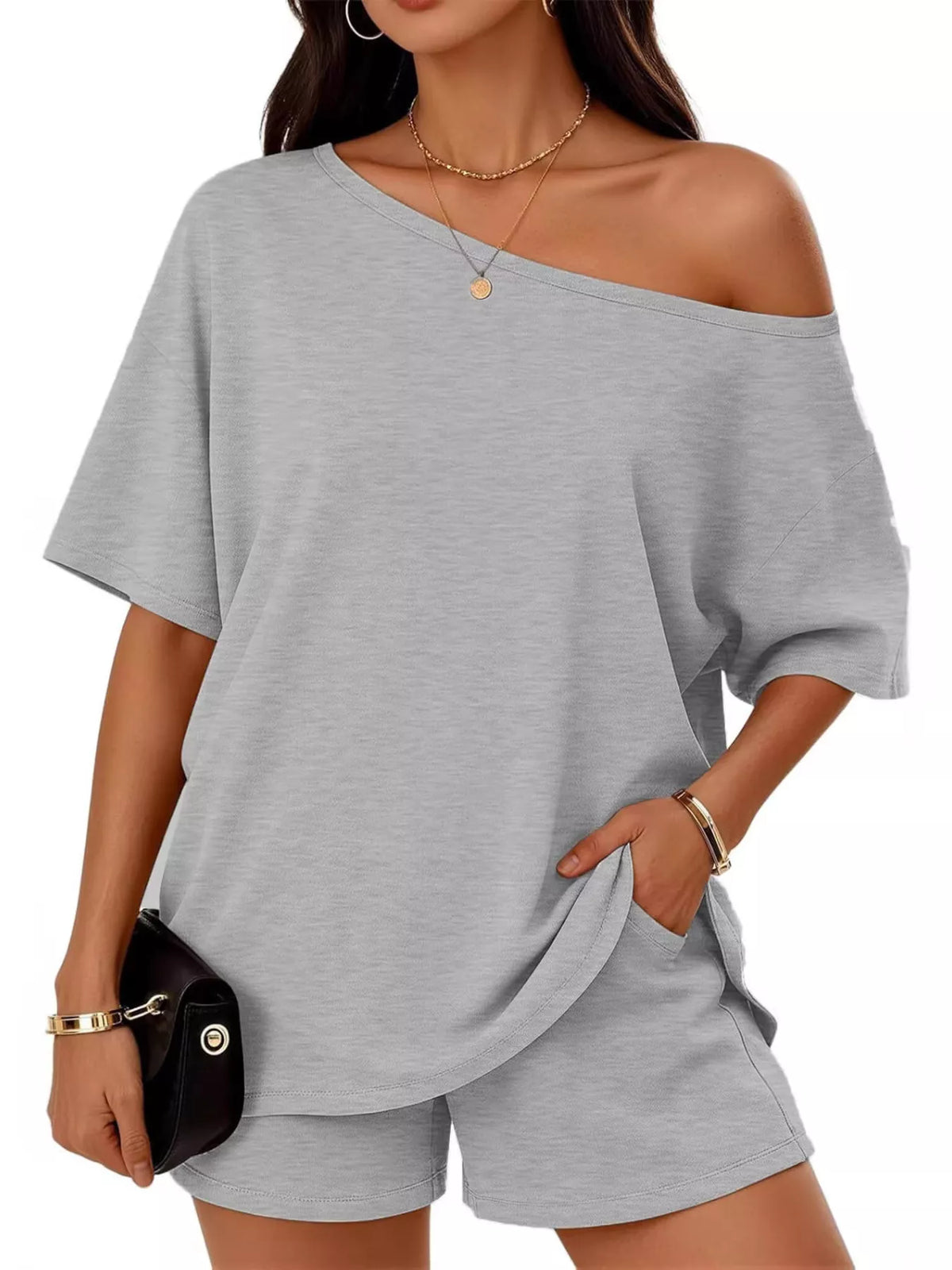 Woman wearing a gray off-shoulder top and shorts set on a white background
