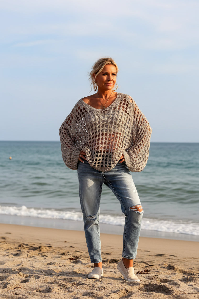 Person wearing a beige crochet sweater by the ocean