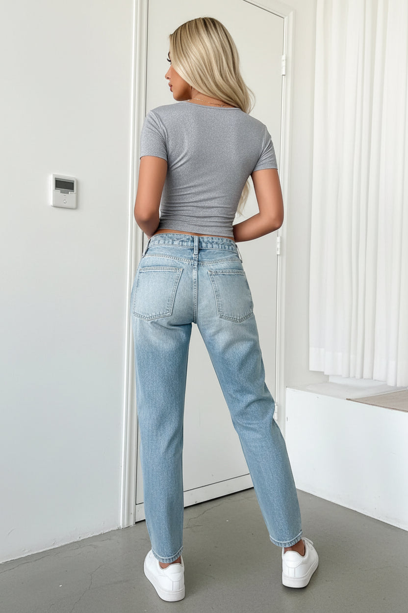 Person wearing a gray t-shirt and blue jeans in a neutral setting