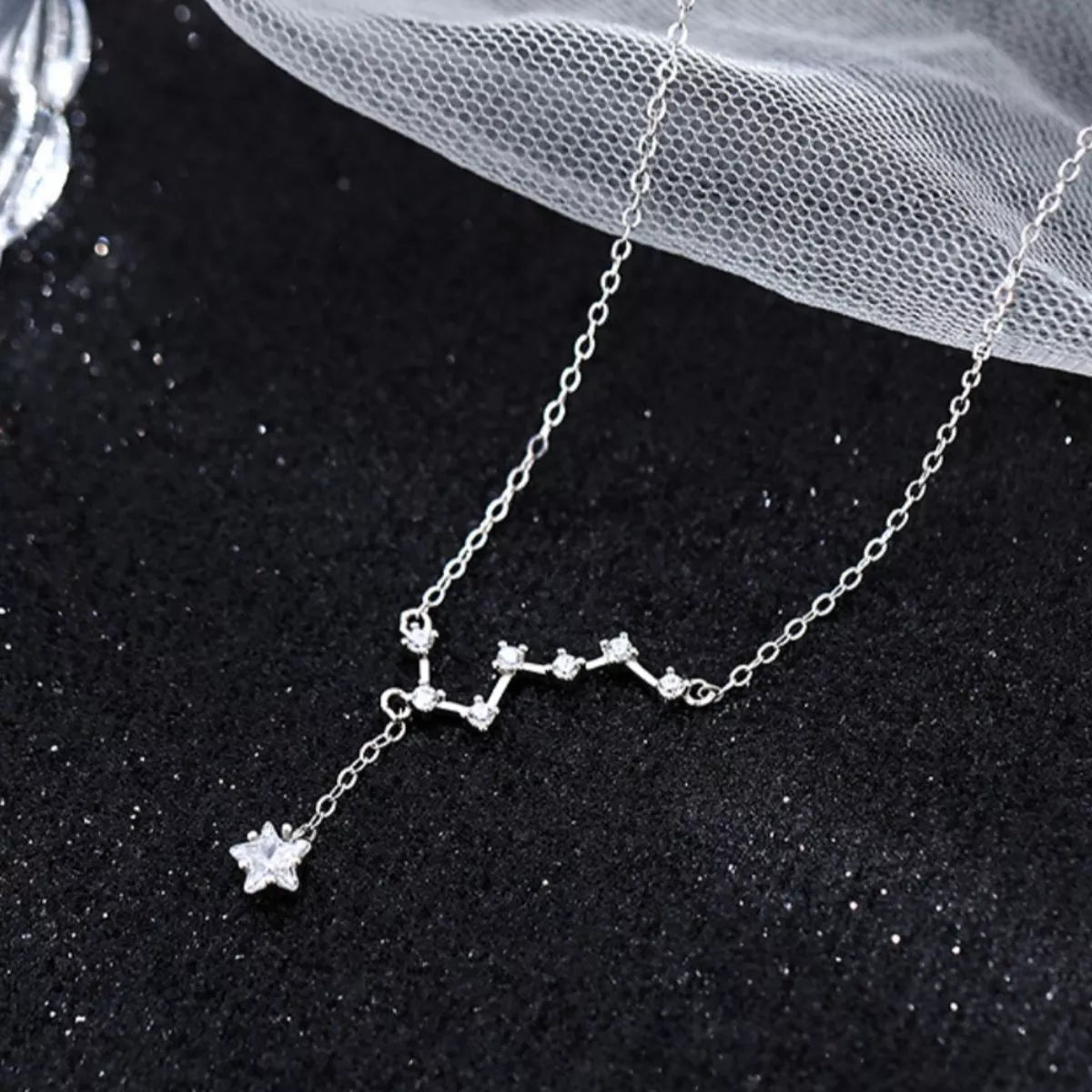 Zircon-encrusted star necklace shimmering in natural light black background