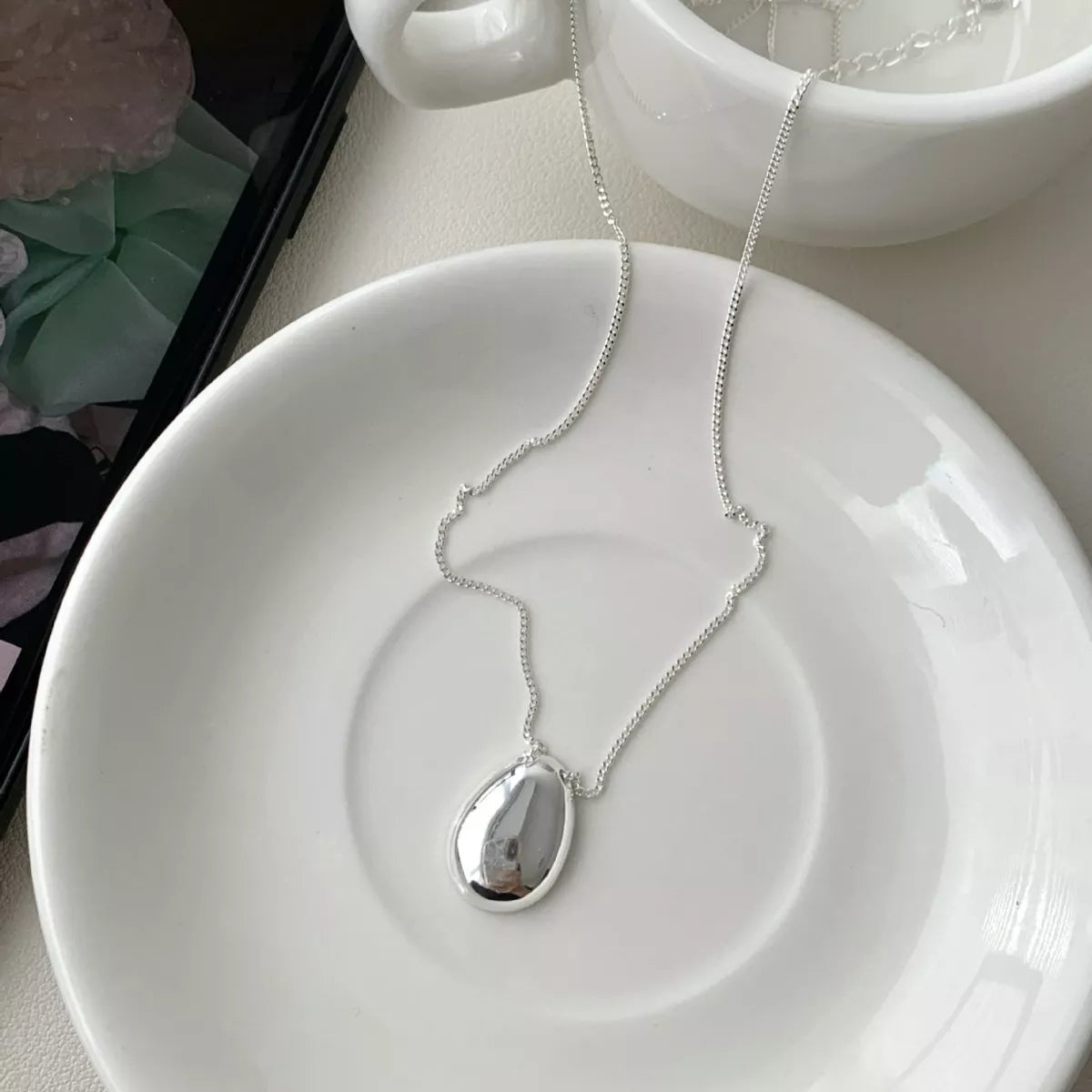 Close-up texture of smooth sterling silver pendant and delicate chain links