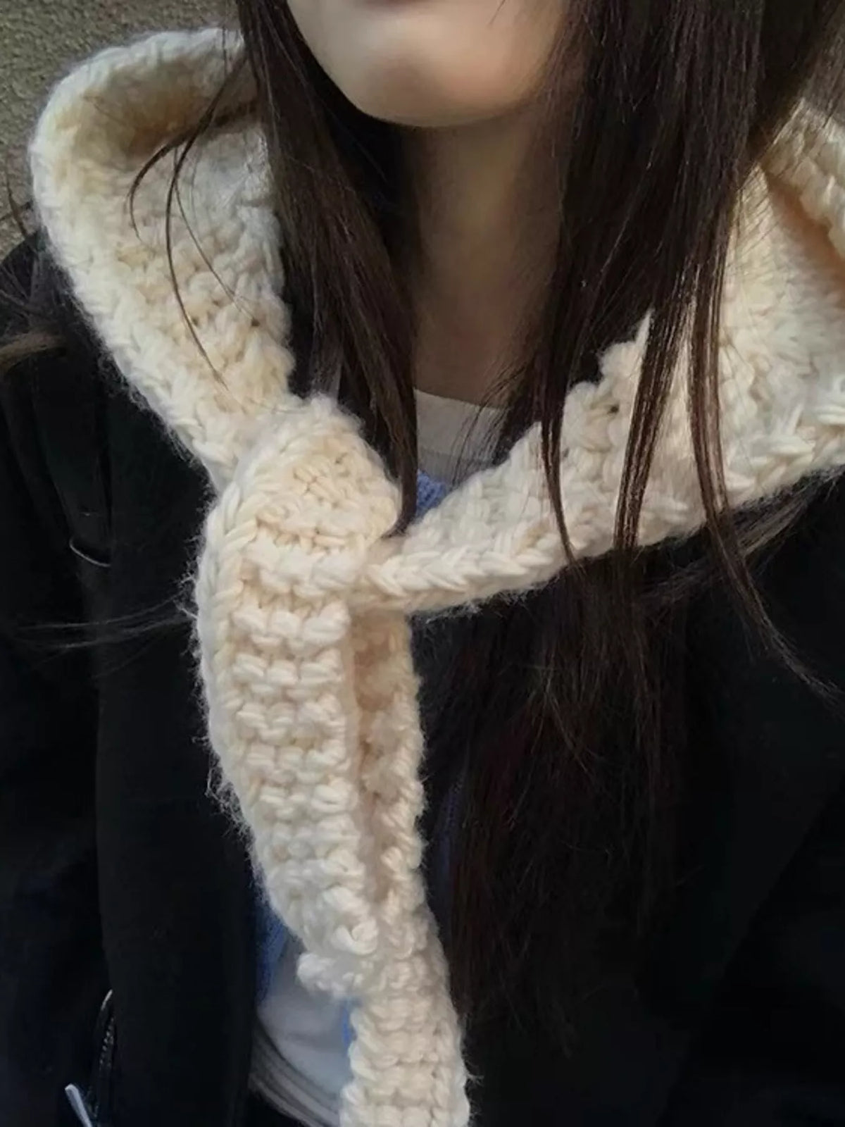 Close-up textured knitted hooded scarf hat with hood up and scarf tails draped