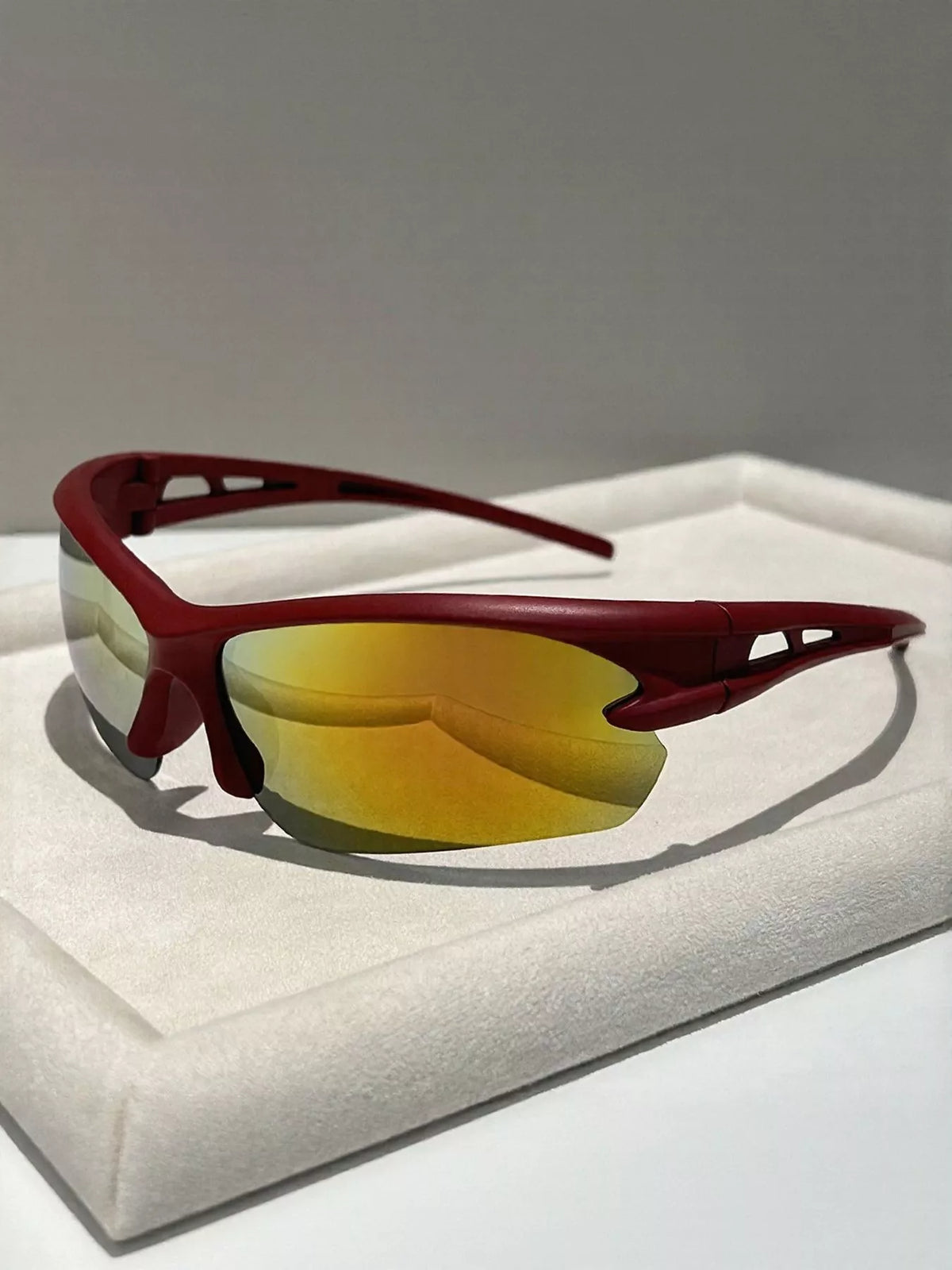 Red sunglasses with yellow-tinted lenses on a white surface
