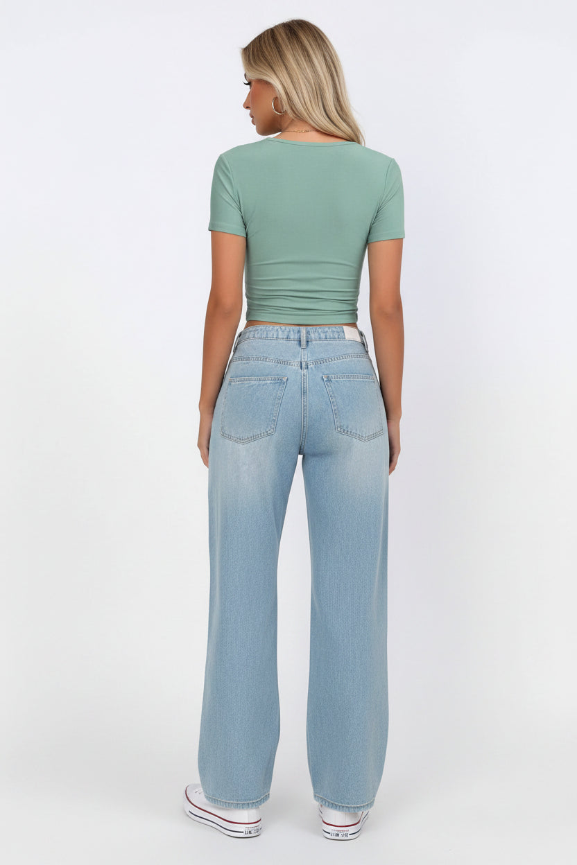 Person wearing a green top and blue jeans on a white background