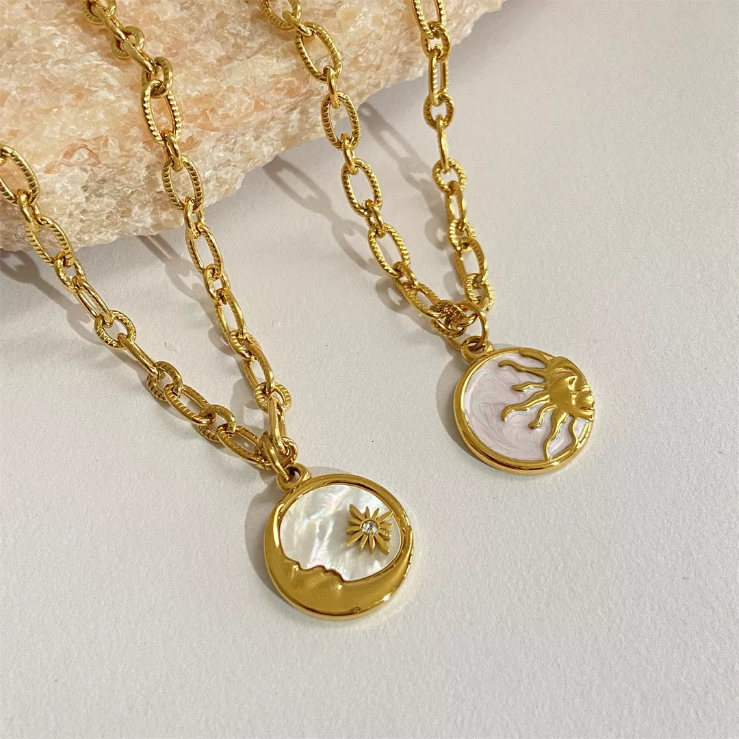Two gold necklaces with circular pendants on a light background