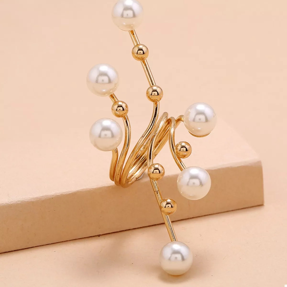 Gold and pearl decorative item on a beige background