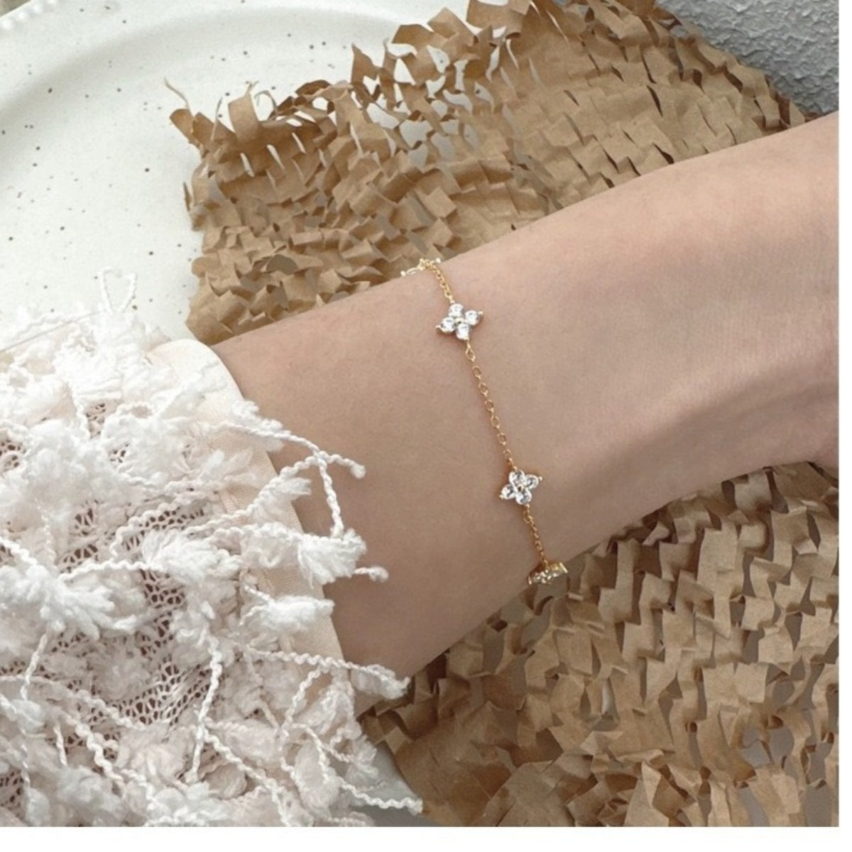 Model stacking the clover bracelet with other chains for bold arm candy