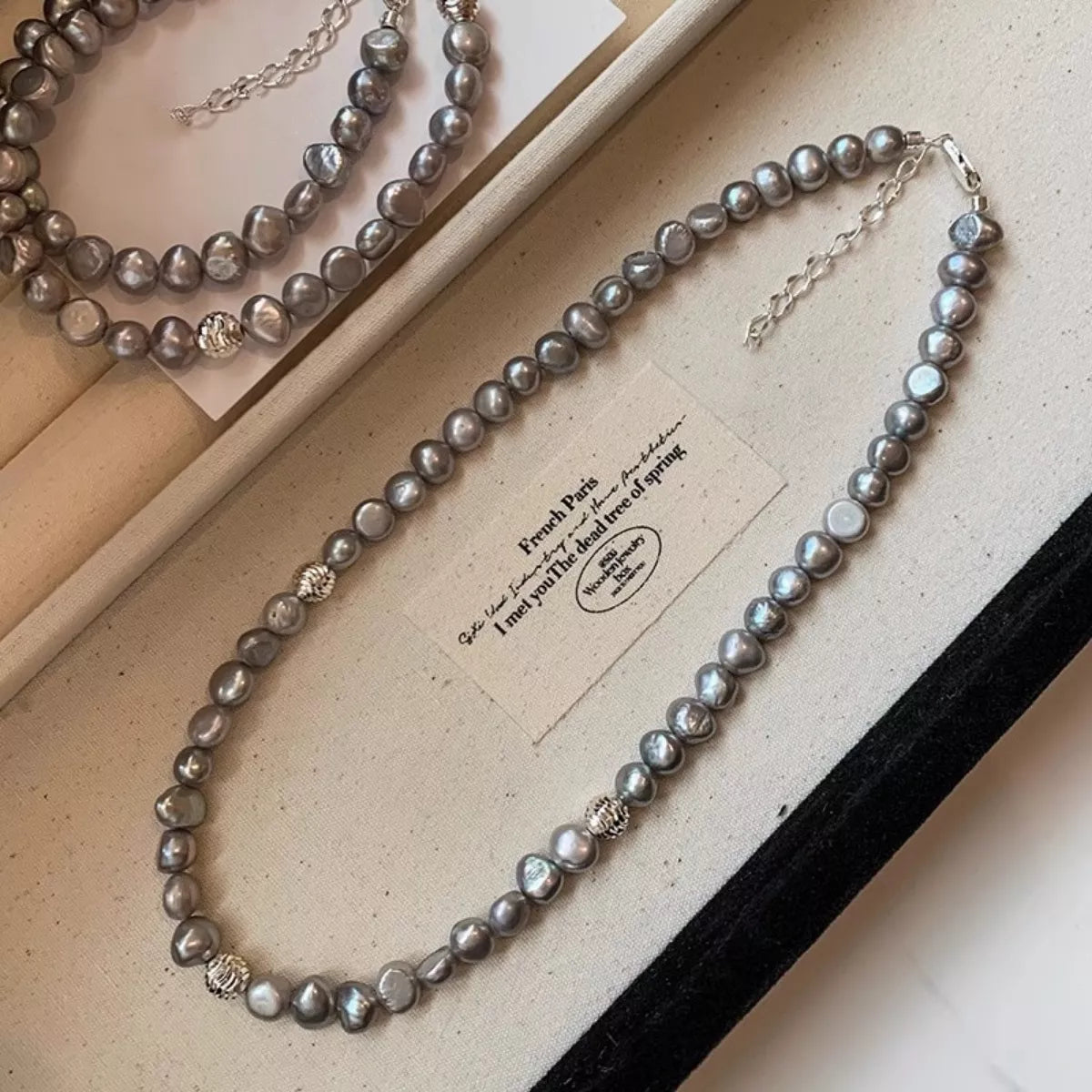 Pearl necklace on a jewelry box with brand name visible