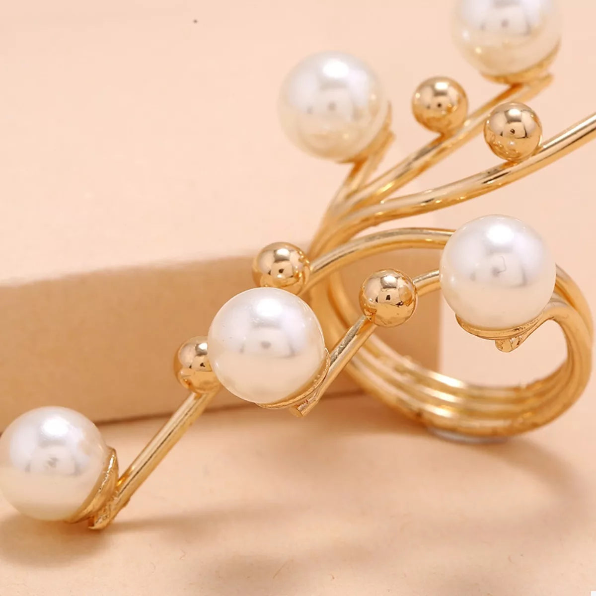 Gold bracelet with pearls on a beige background