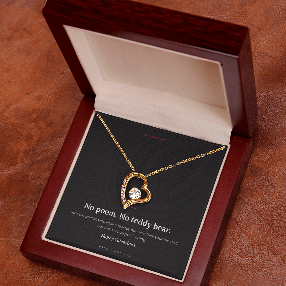 Yellow gold heart pendant and card in the mahogany box, angled on warm brown wood