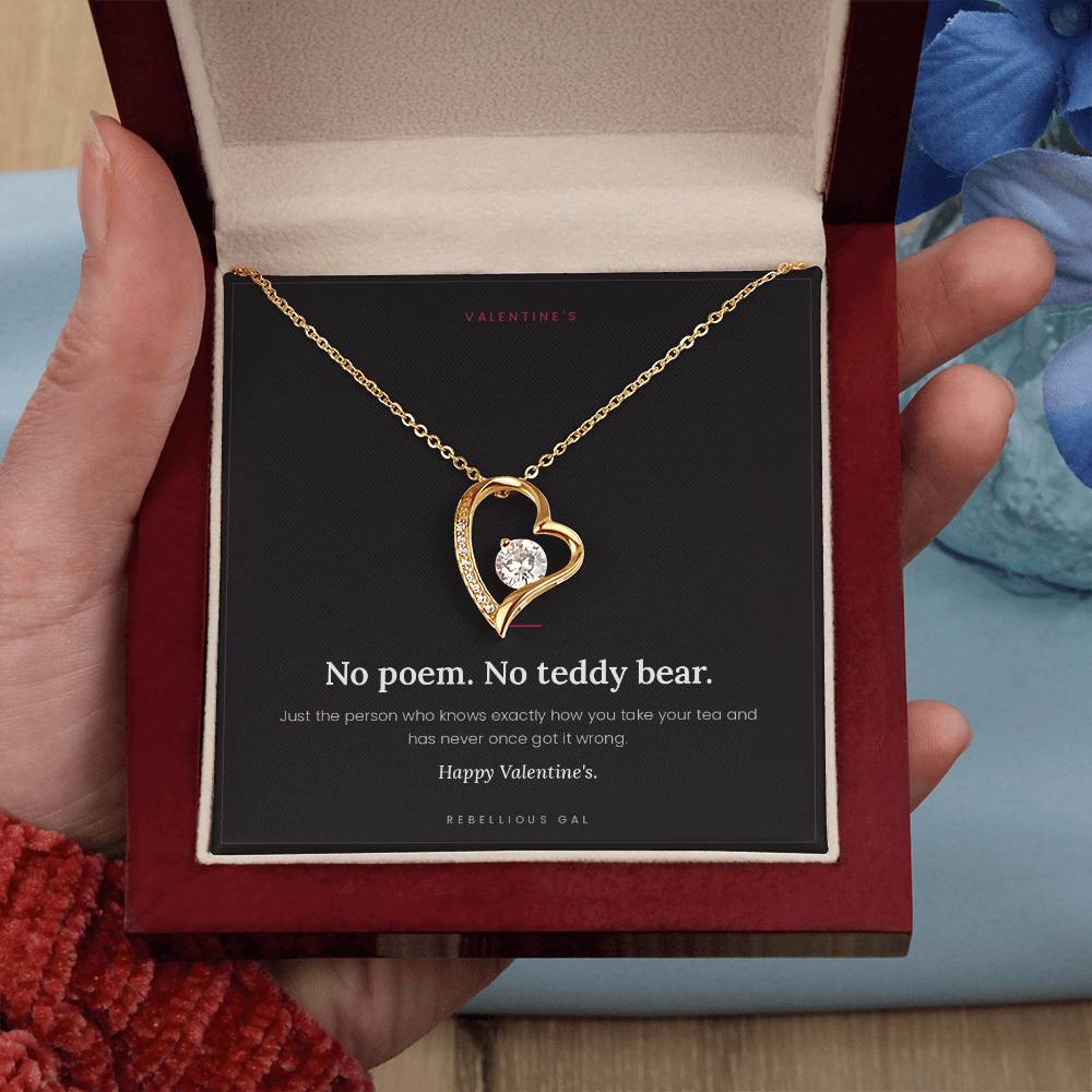 Gold heart pendant set with a clear stone, in an open red gift box held above a No Poem Valentine's card