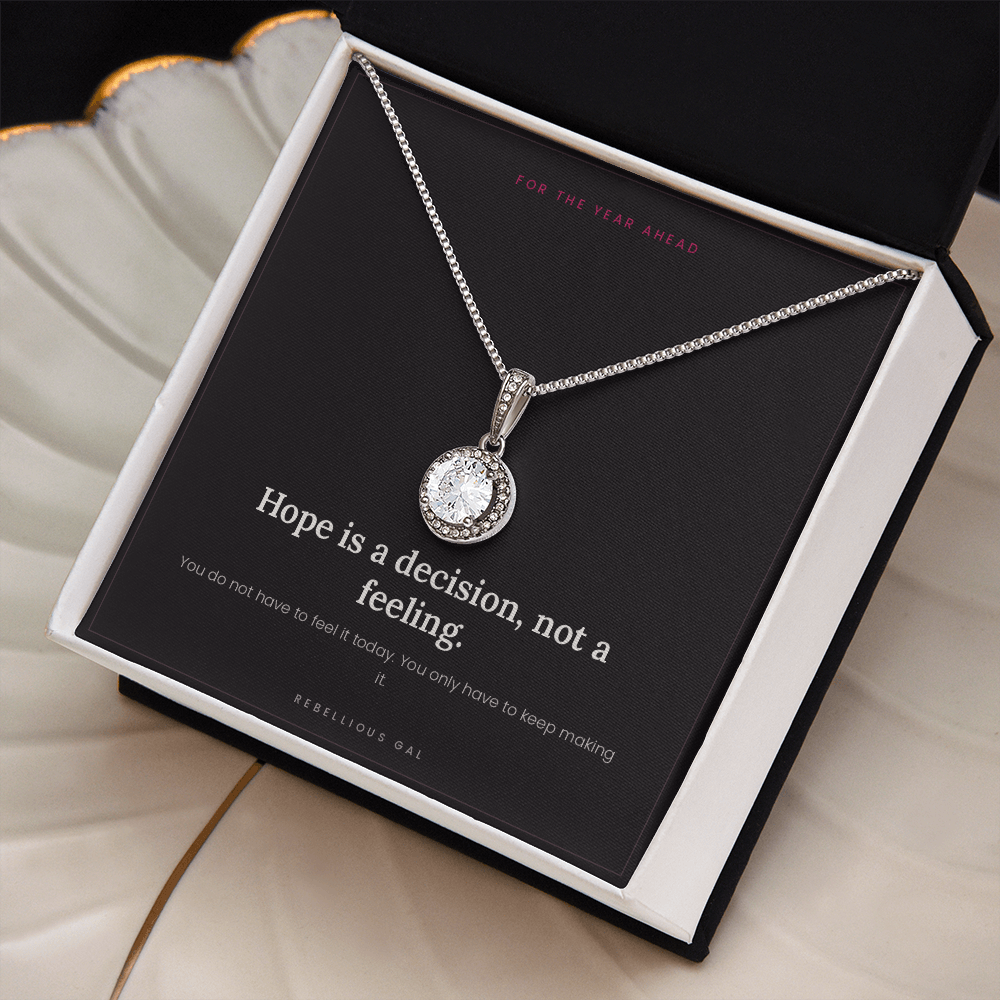 Silver halo pendant in an open white box beside a gold-rimmed scalloped ceramic dish