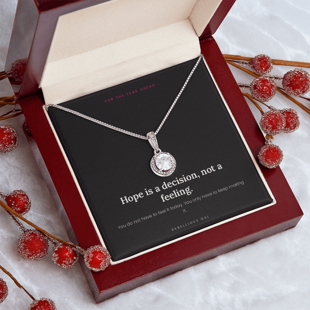 Silver halo pendant in a tilted mahogany box framed by frosted red berry sprigs