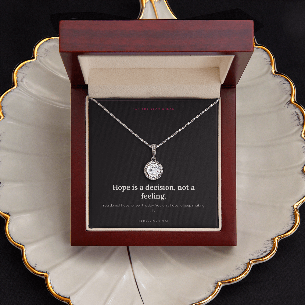 Open mahogany box with the silver halo pendant resting on a gold-rimmed scalloped dish