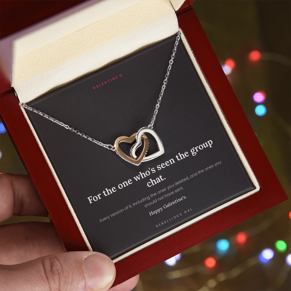 Hand holding the open mahogany box with the heart pendant necklace, colorful string lights behind