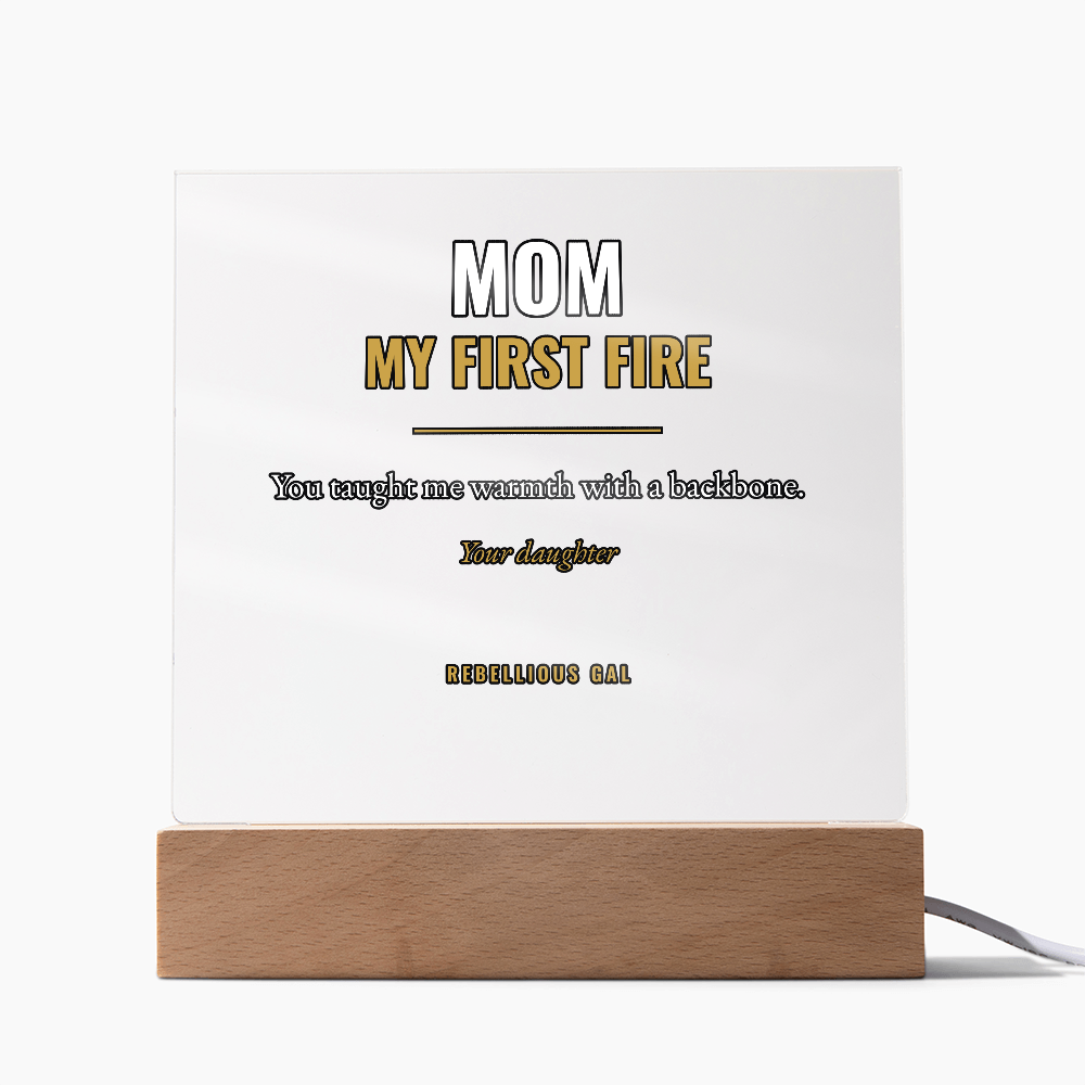Unlit acrylic plaque reading Mom My First Fire, grey cord trailing across plain white