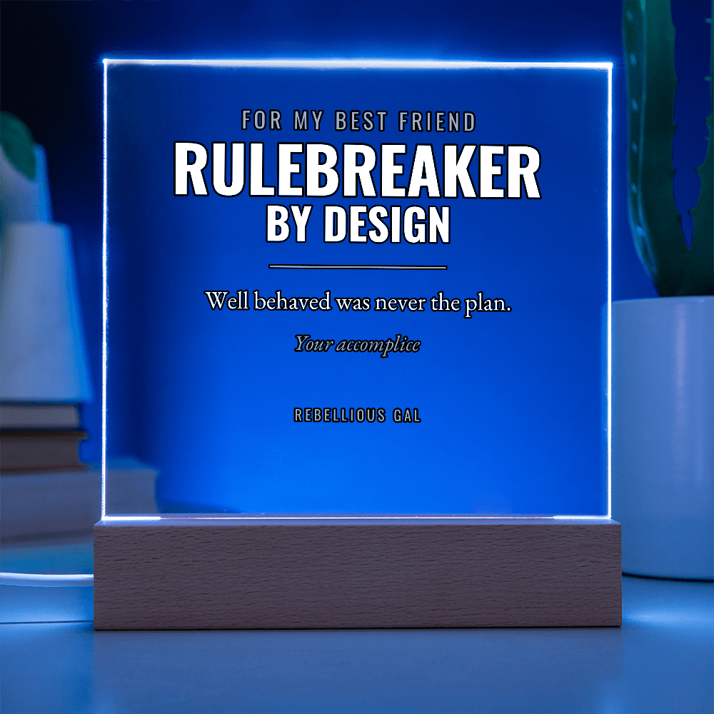 Plaque edge-lit bright blue in a dark room, potted cactus and books behind