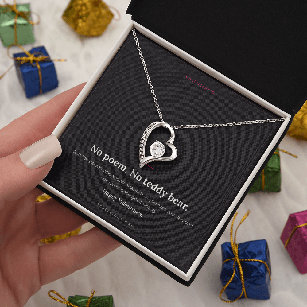 aSilver heart pendant and No Poem card in a gift box held among wrapped presents