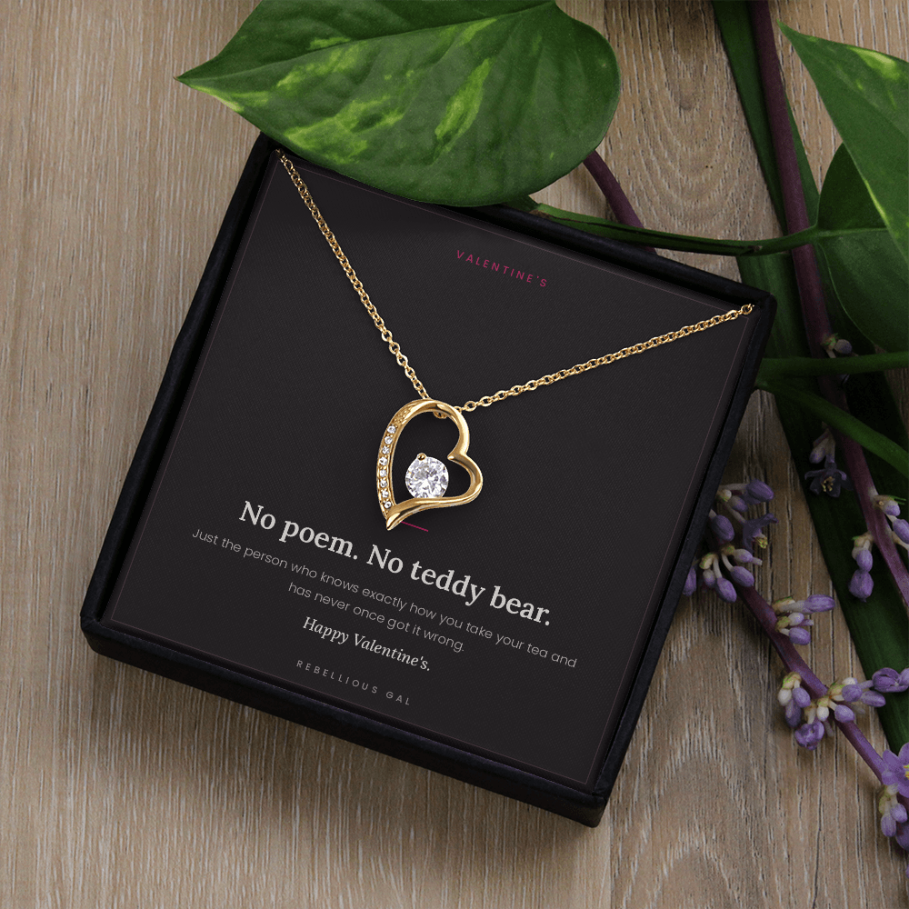 aGold heart pendant and No Poem card in a gift box on wood with trailing foliage