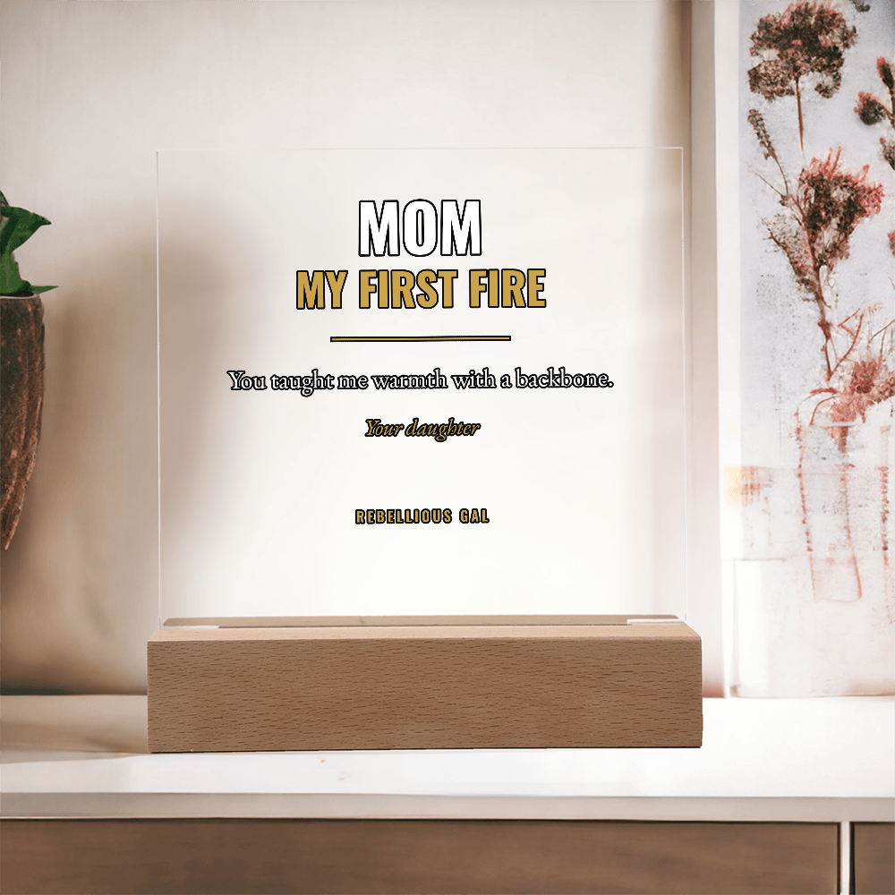 Terracotta vase and tall dried rust-pink stems stand either side of the unlit plaque