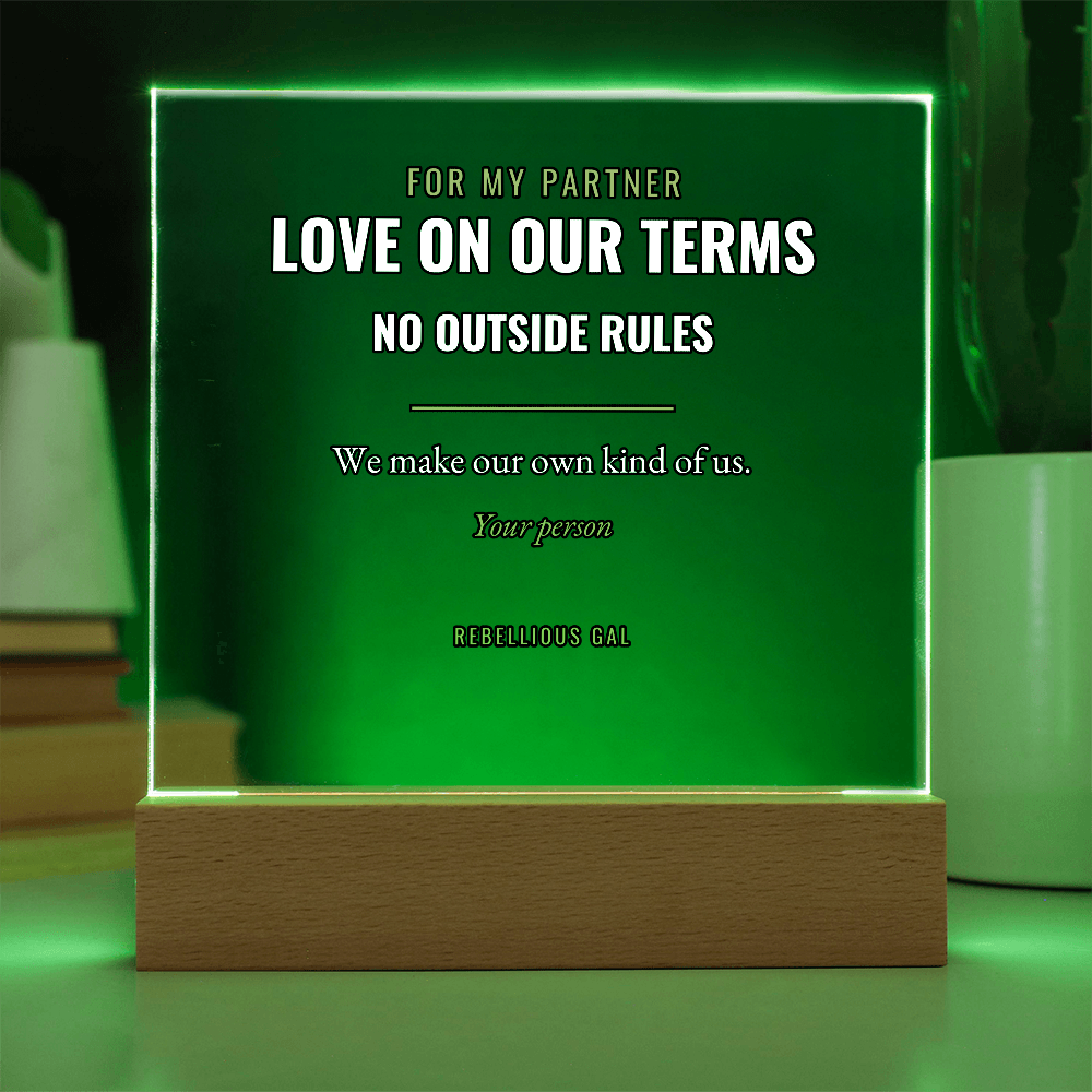 Stacked books left, potted cactus right, green light washing the lettered panel between them