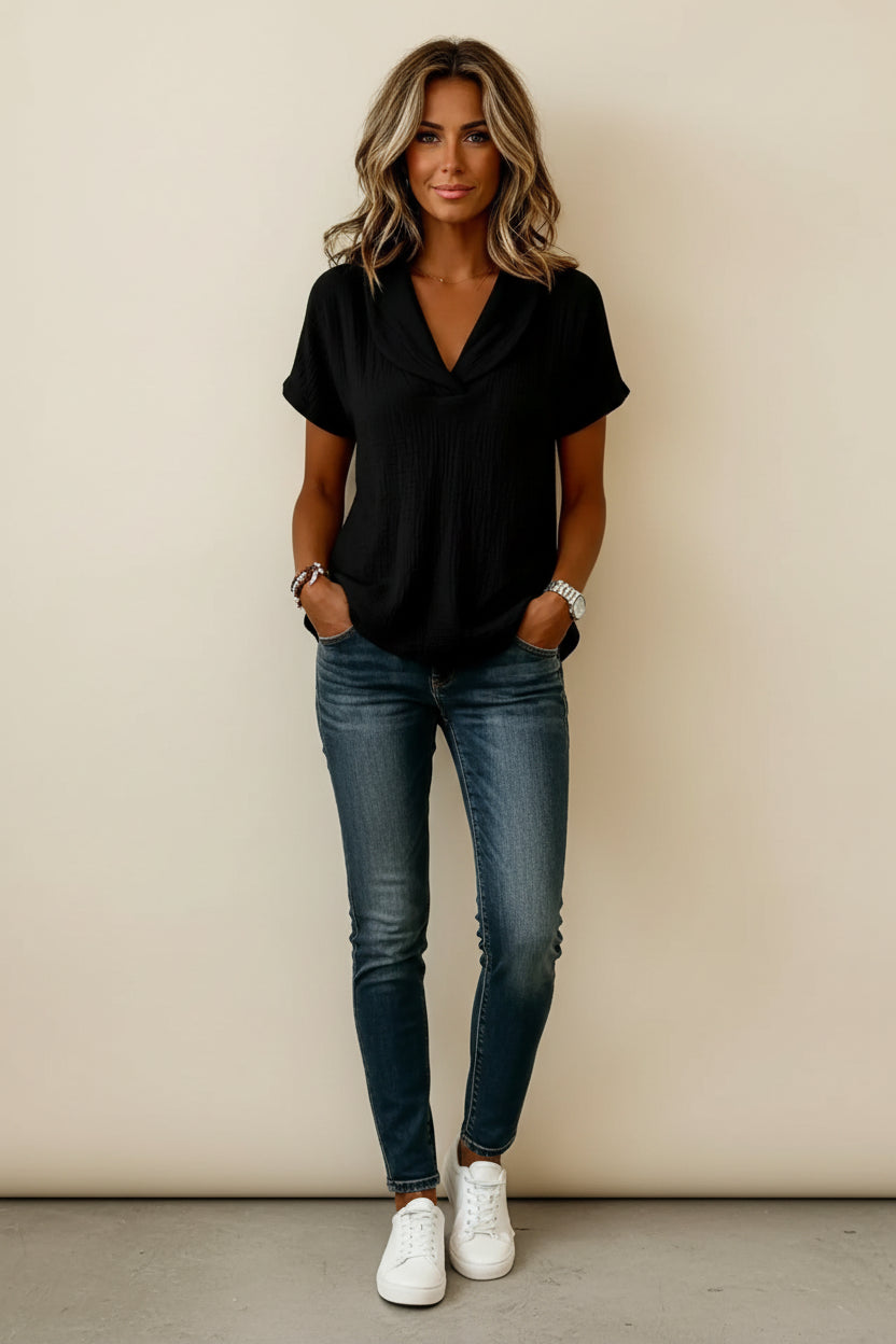 Person wearing a black short-sleeve top with a plain background