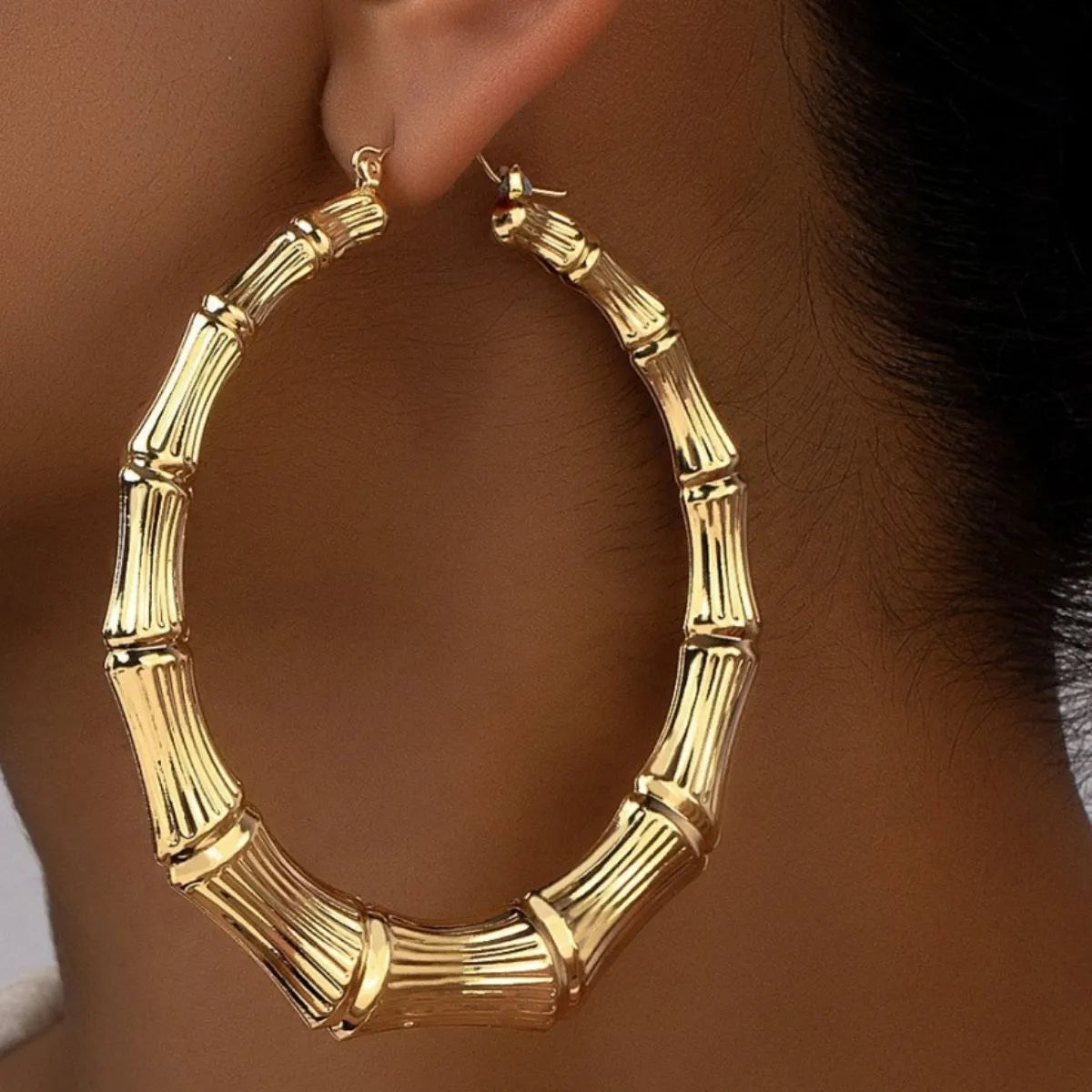 Close-up textured detail on large gold plated hoop earrings stainless steel shine