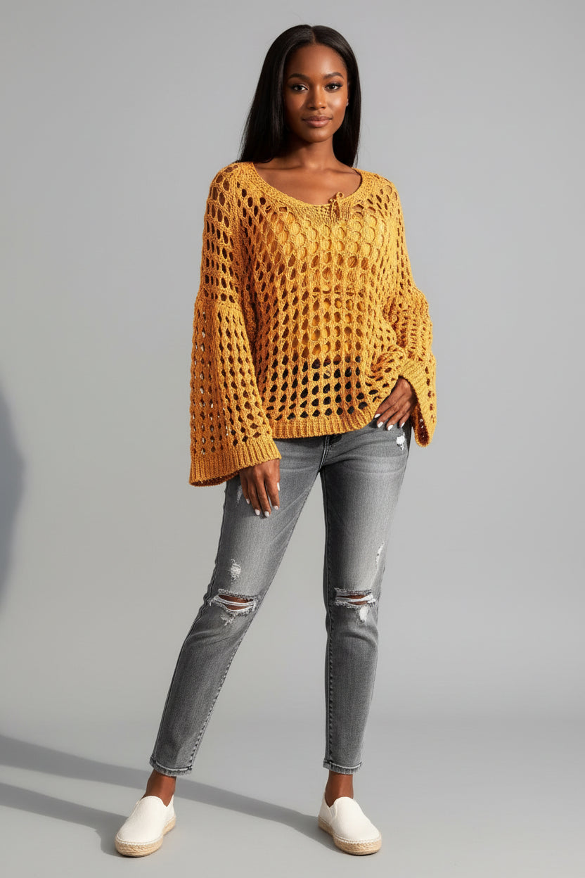 Close-up of a person wearing a yellow crochet sweater with a blurred background