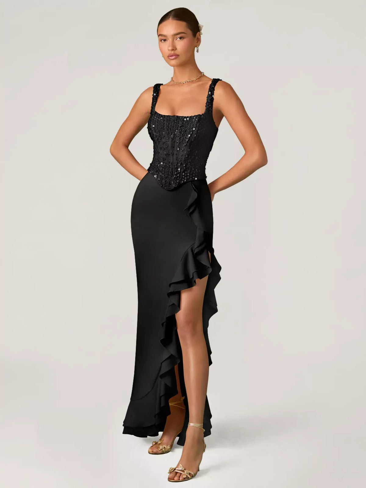 Woman wearing a black evening gown with a sequined top on a white background