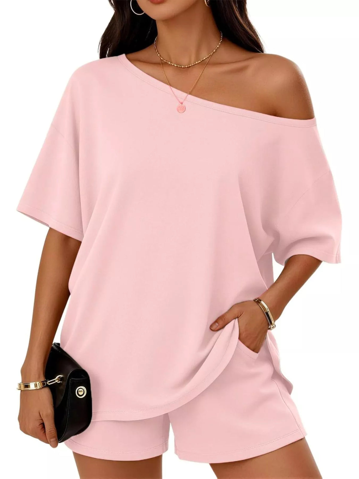 Woman wearing a pink off-shoulder top and shorts set on a white background