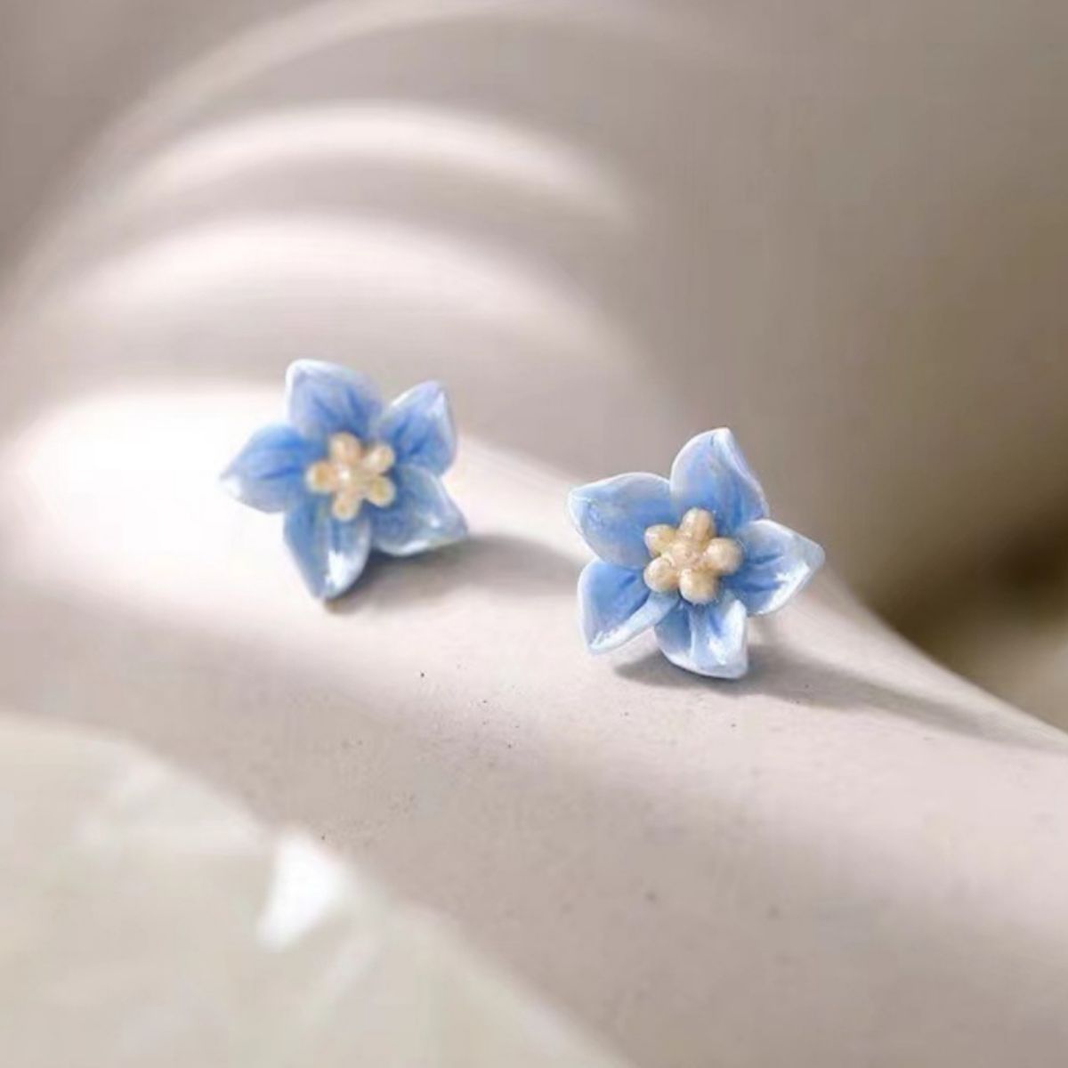 Minimalist flower stud earrings worn on ear