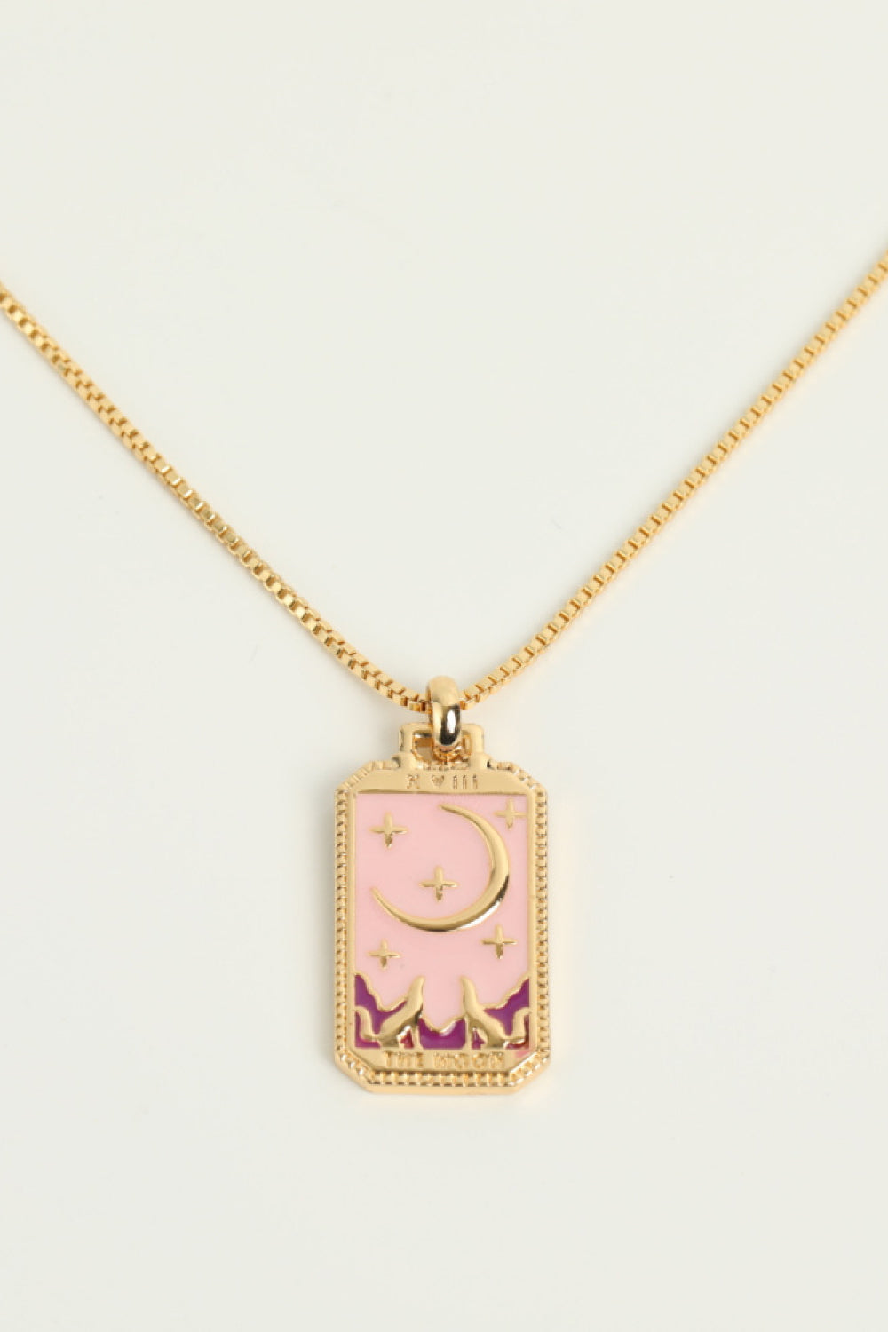 Necklace with a pink pendant featuring a moon and star design on a light gray background