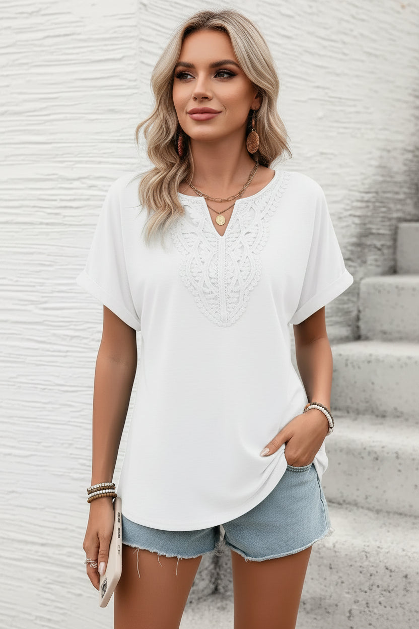 Woman wearing a white blouse and denim shorts against a light gray wall.