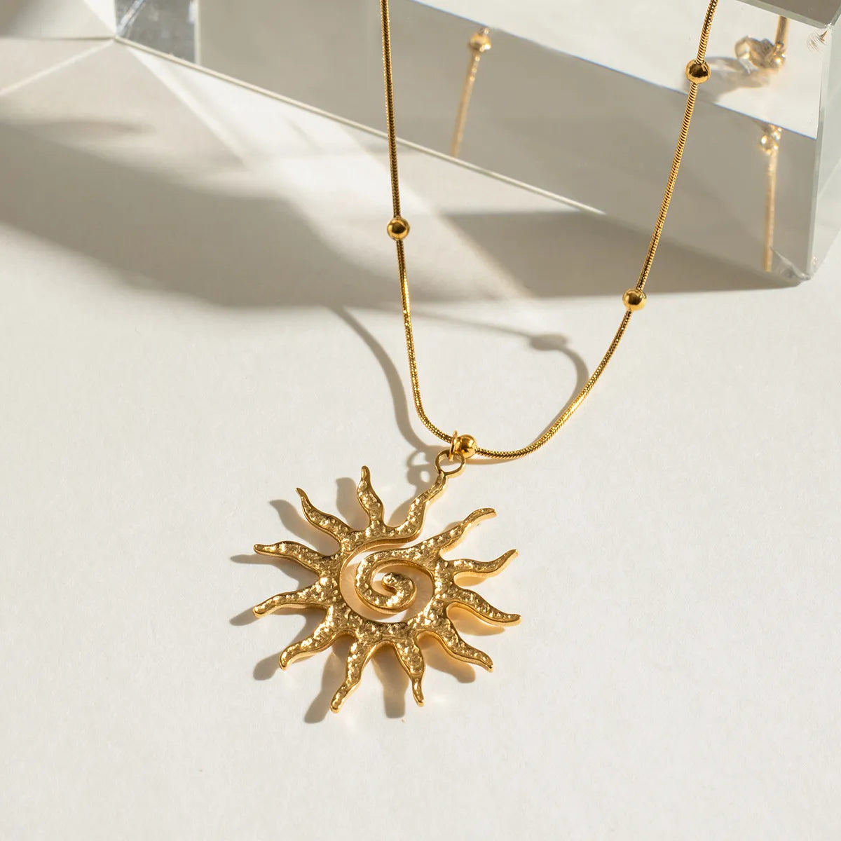 sun pendant necklace, on a white background close up shot of back look in gold