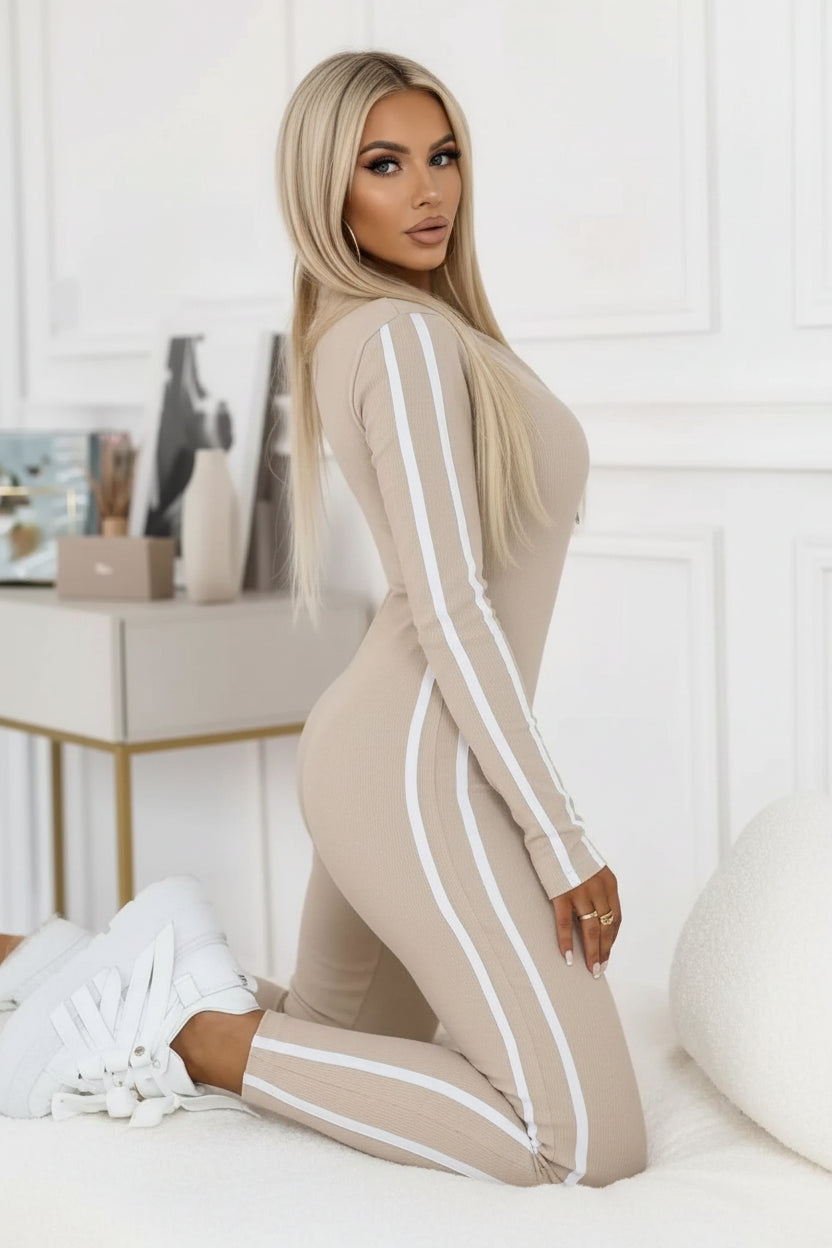 Person wearing a beige tracksuit with white stripes in a room setting.