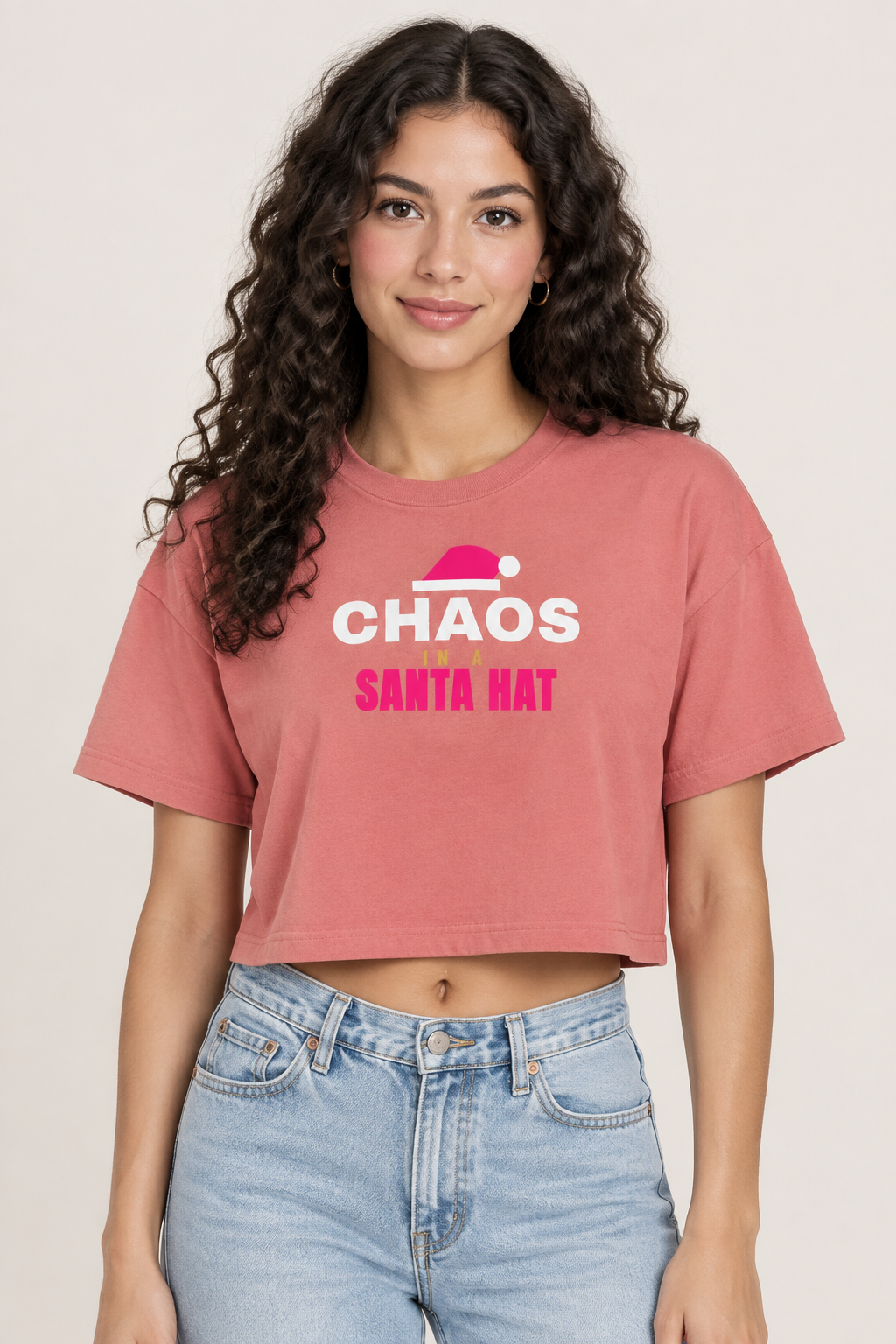 Woman with long dark curls in the red sorbet Chaos Santa Hat crop top, pale backdrop