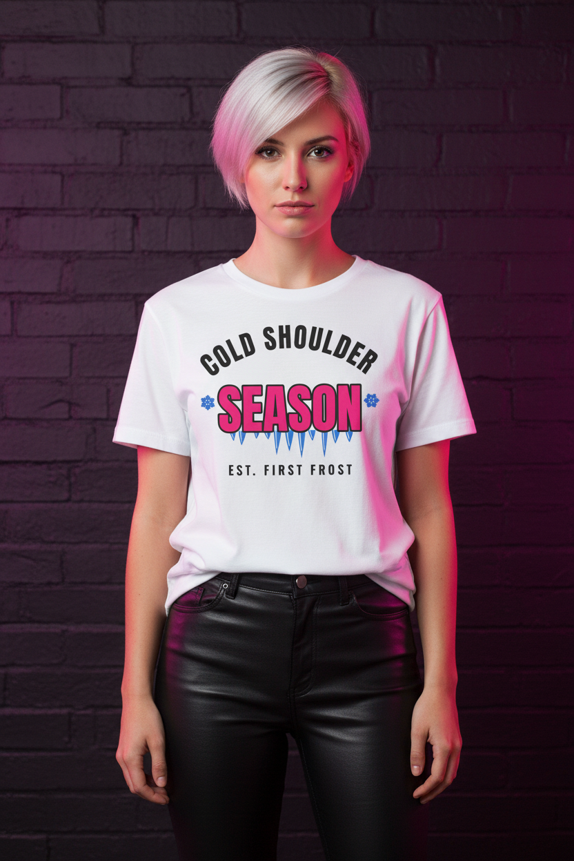 Woman with a pink pixie cut in the white Cold Shoulder Season tee, brick wall