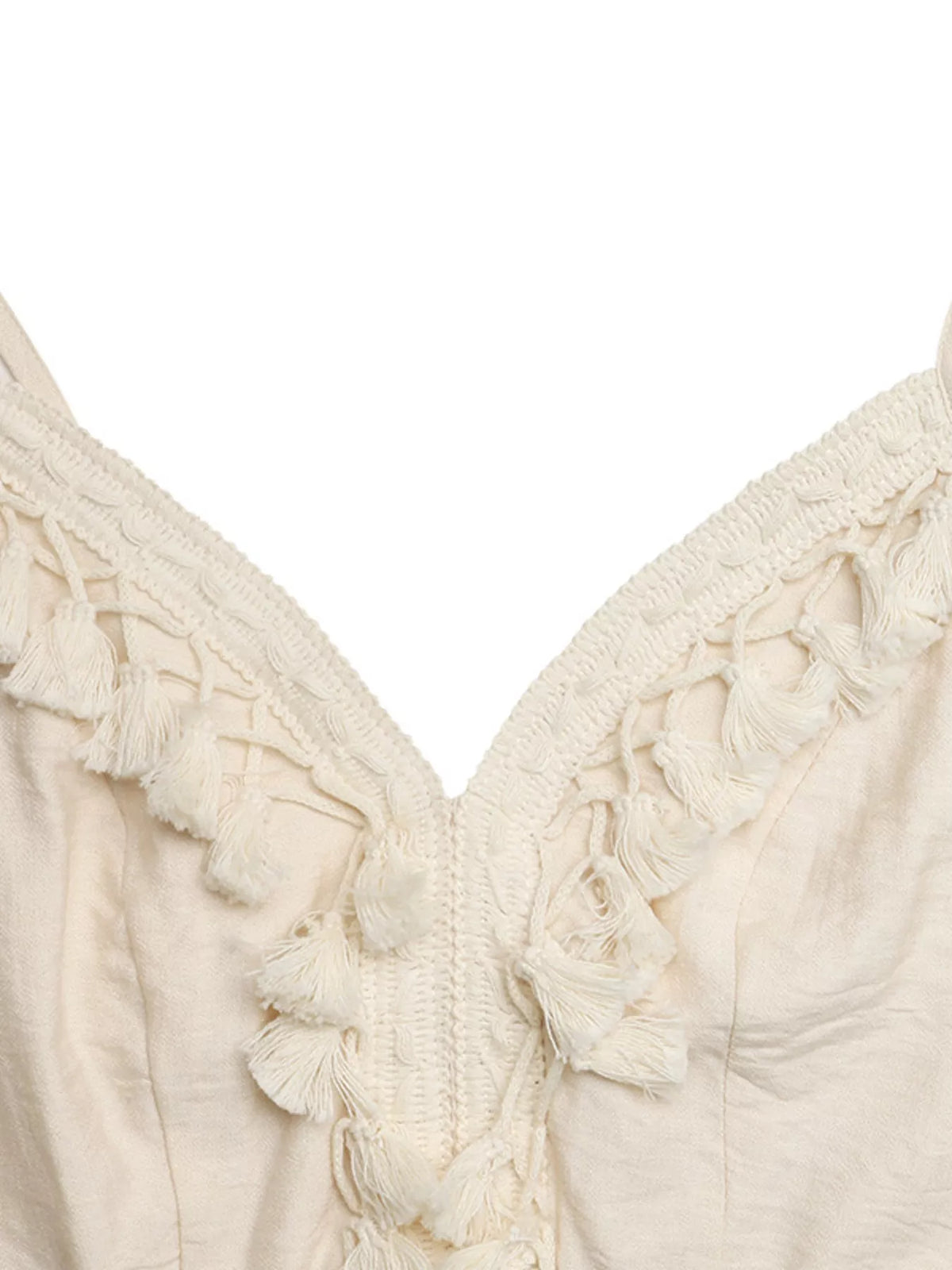 Close-up of a cream-colored top with tassel details on a white background