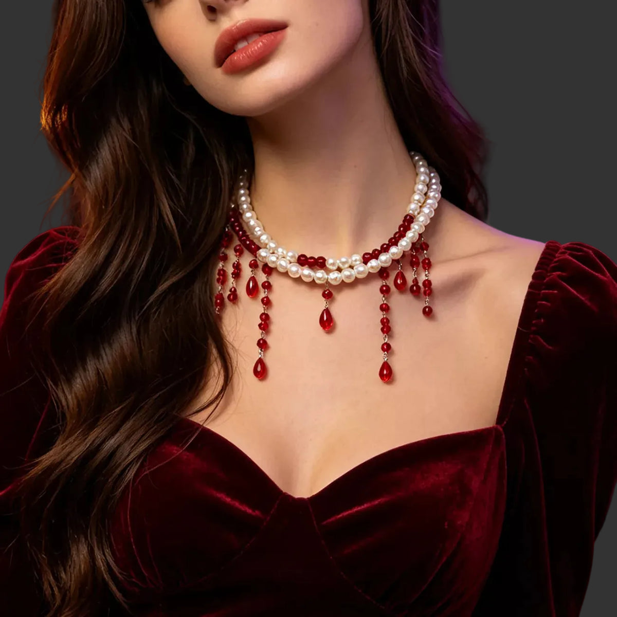 Pearl choker with red beaded drips worn with a burgundy velvet dress