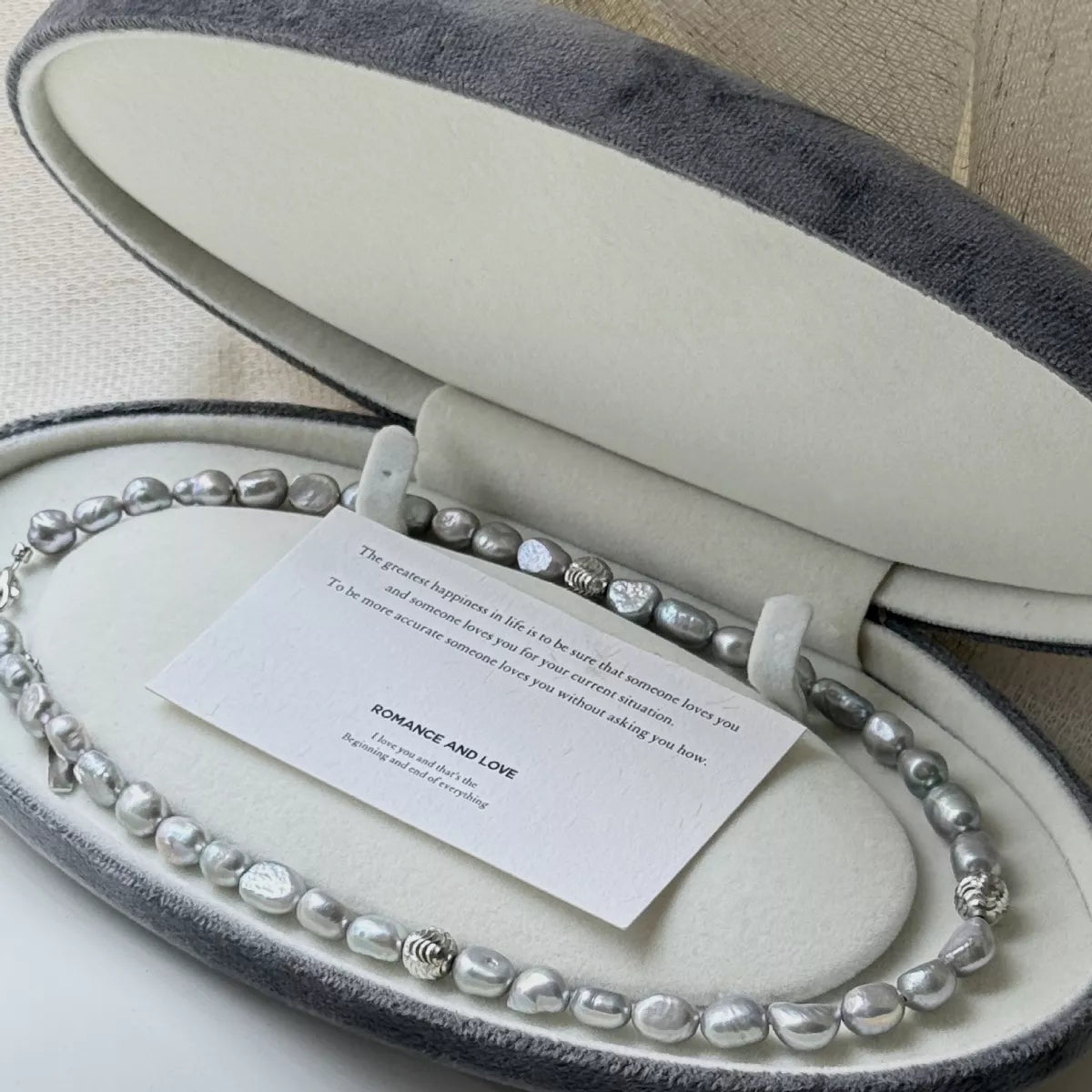 Pearl necklace in an open jewelry box with a card inside