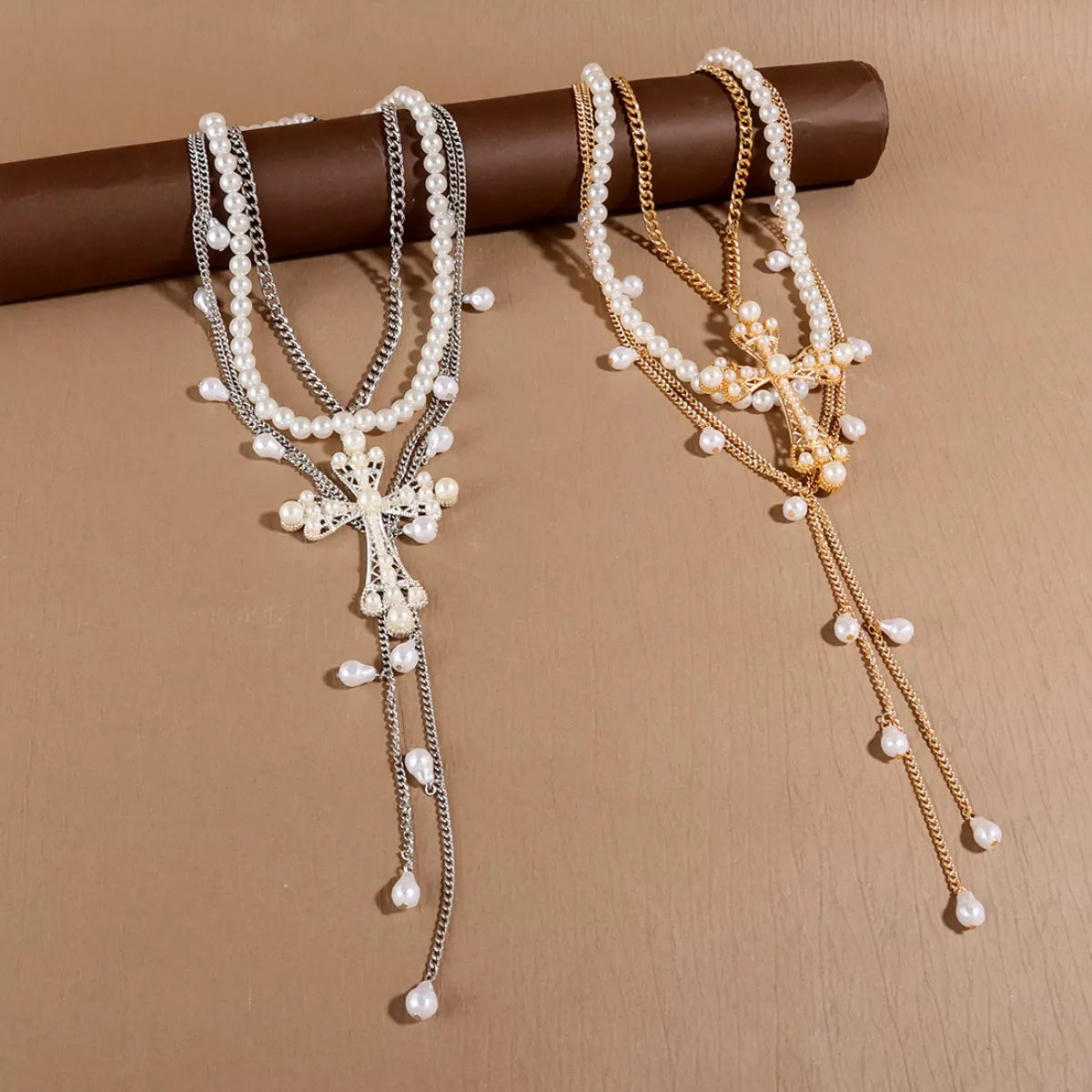 Two pearl necklaces with crosses on a brown surface, branded 'gritty soul'.