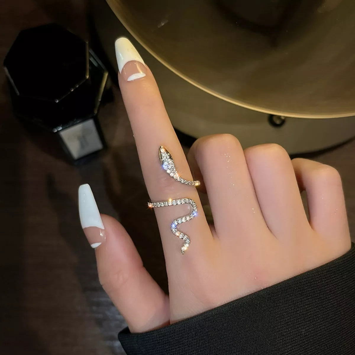 Hand wearing a snake-shaped ring with a blurred background